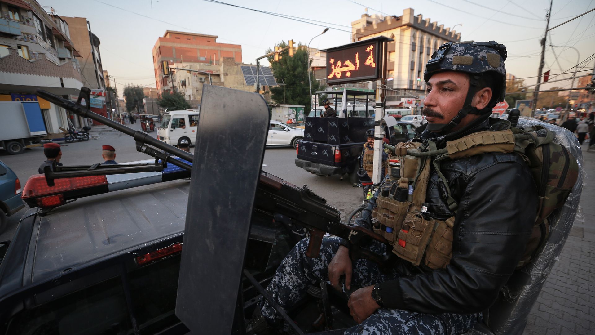 يظهر ضابط شرطة جالسا على مدفع رشاش محمول على سيارة بعد هجوم صاروخي في بغداد.