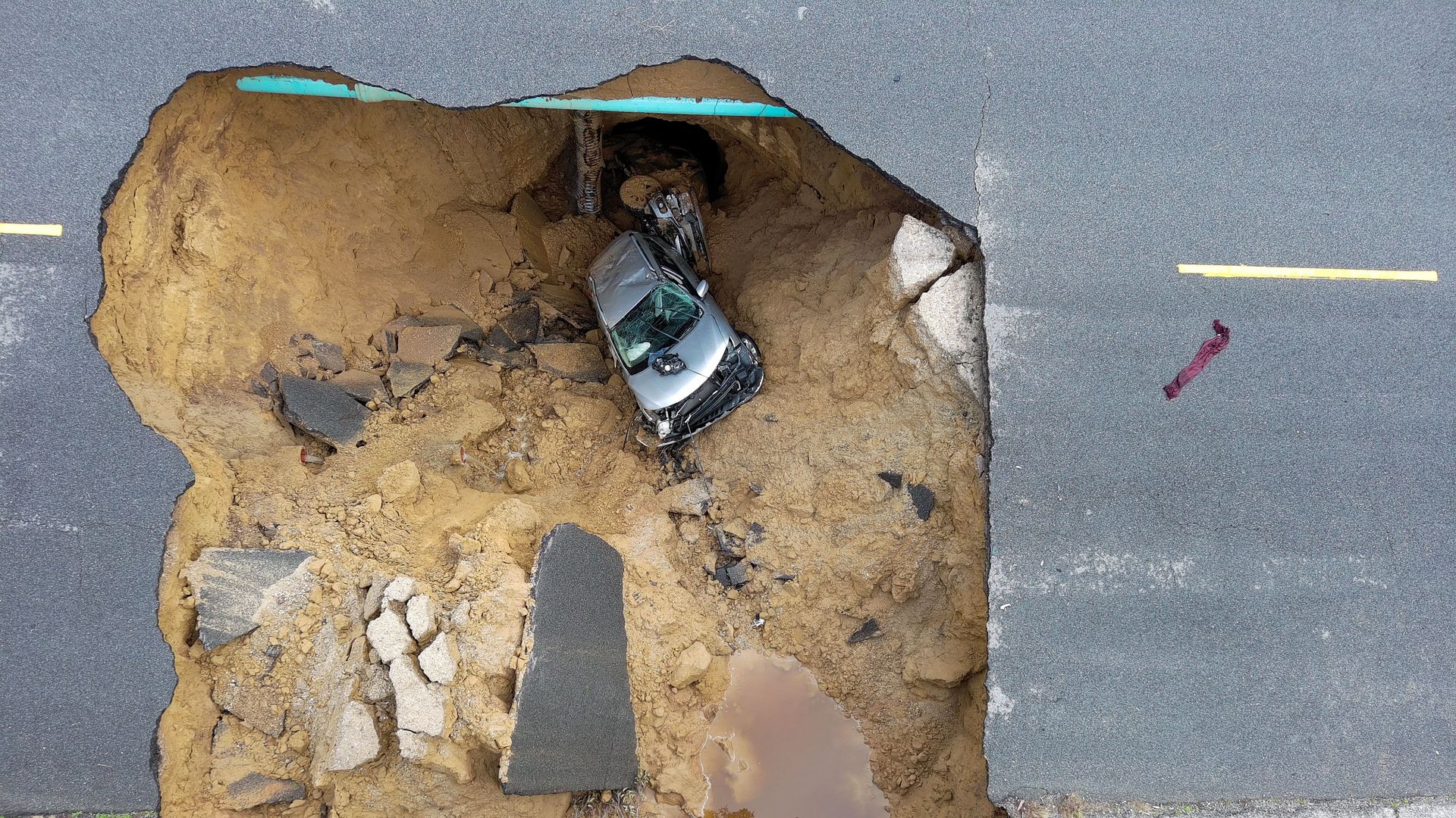This aerial view shows two cars siting in a large sinkhole that opened during a day of relentless rain, January 10, 2023 in the Chatsworth neighborhood of Los Angeles, California.