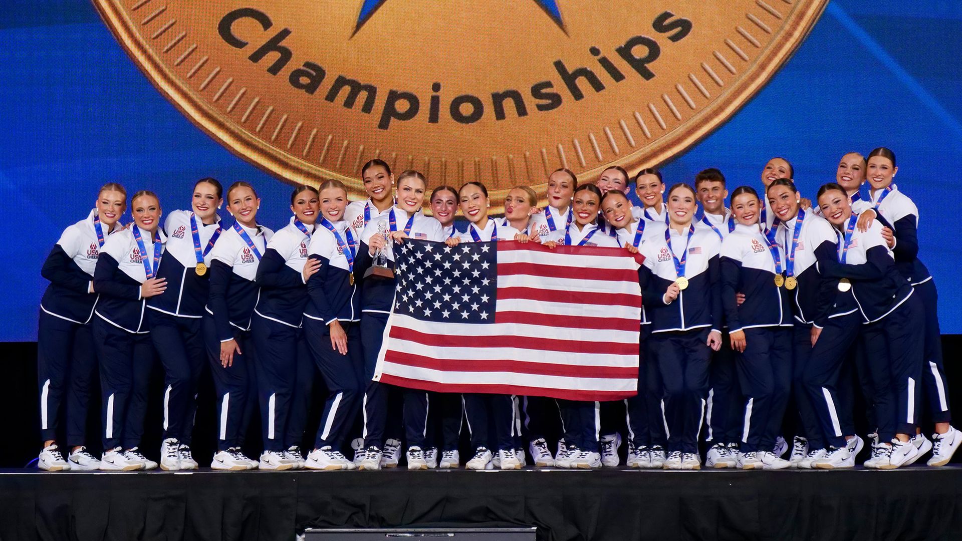Gophers dance team in track suits and medals with an american flag