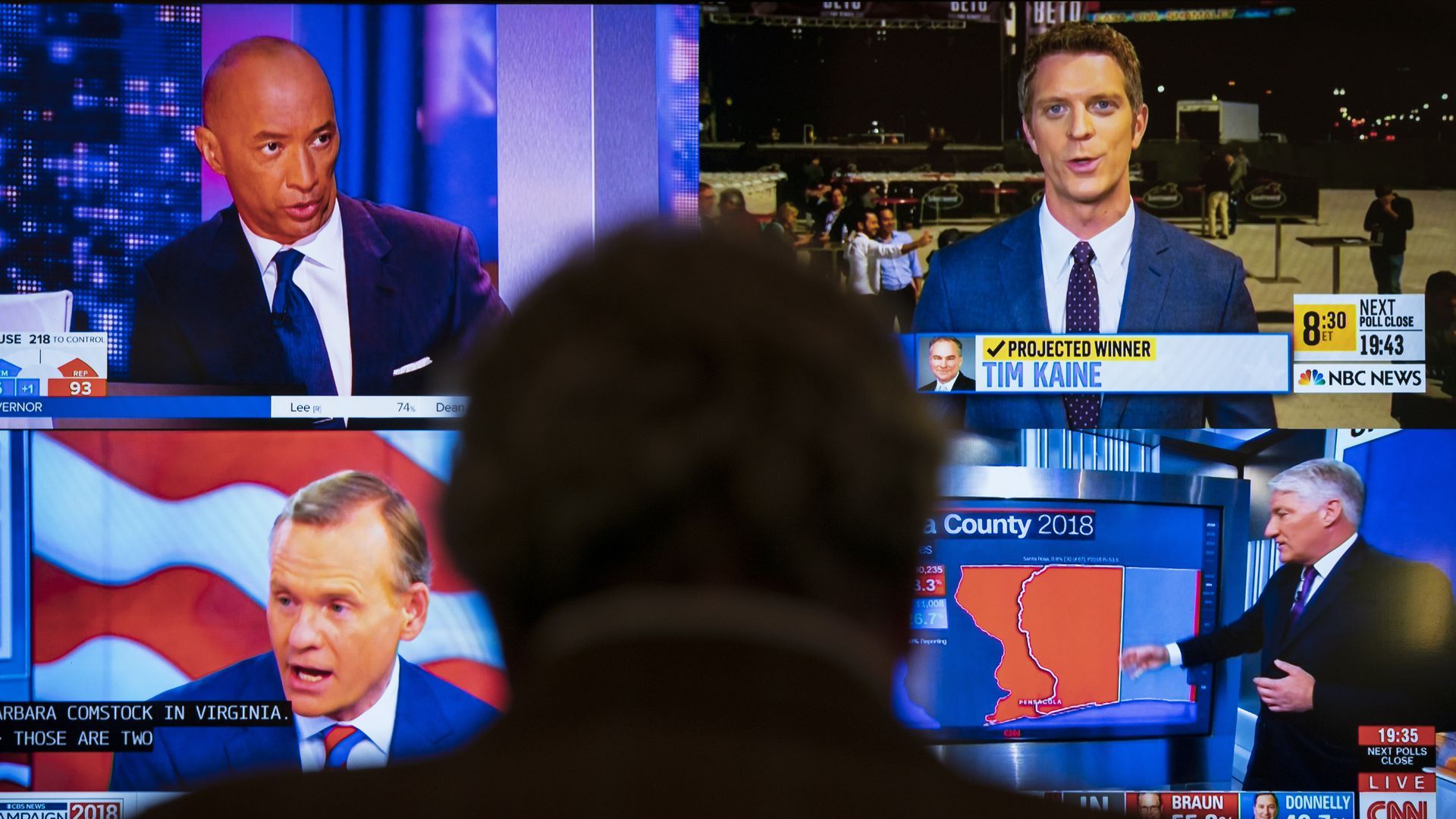 A figure in shadow watches multiple cable news channels.