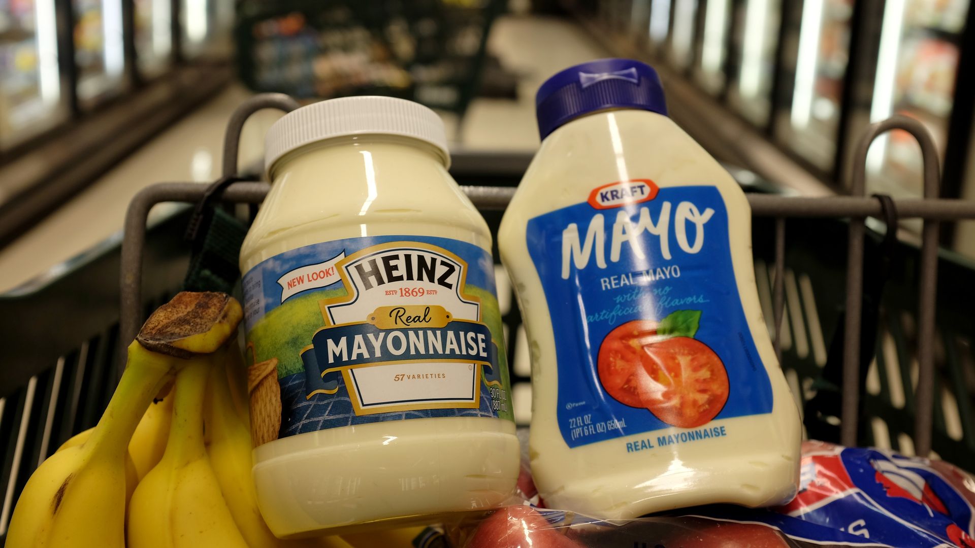 Two jars of mayo in a shopping cart with produce