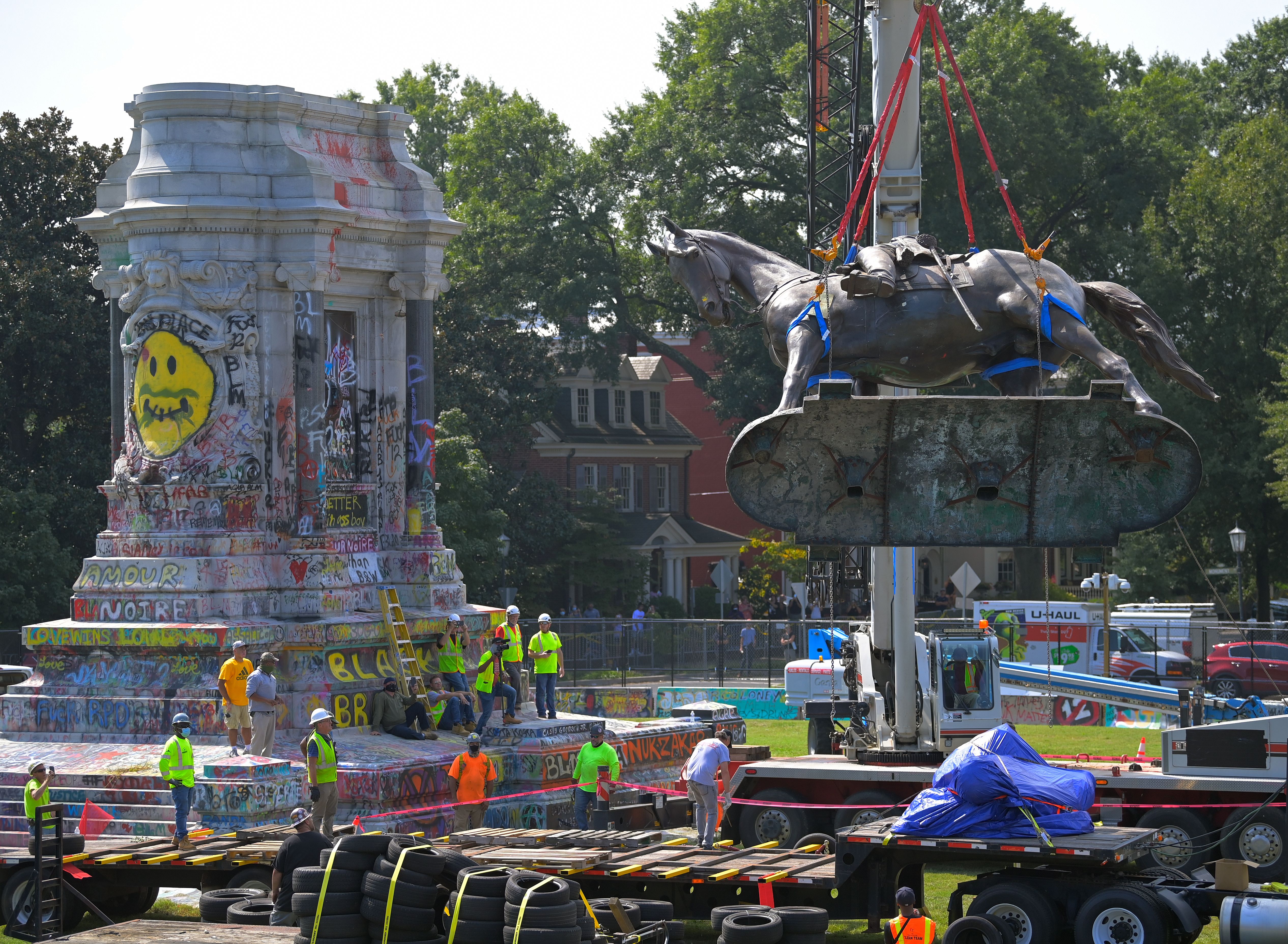 a large crane taking down a monument of a horse
