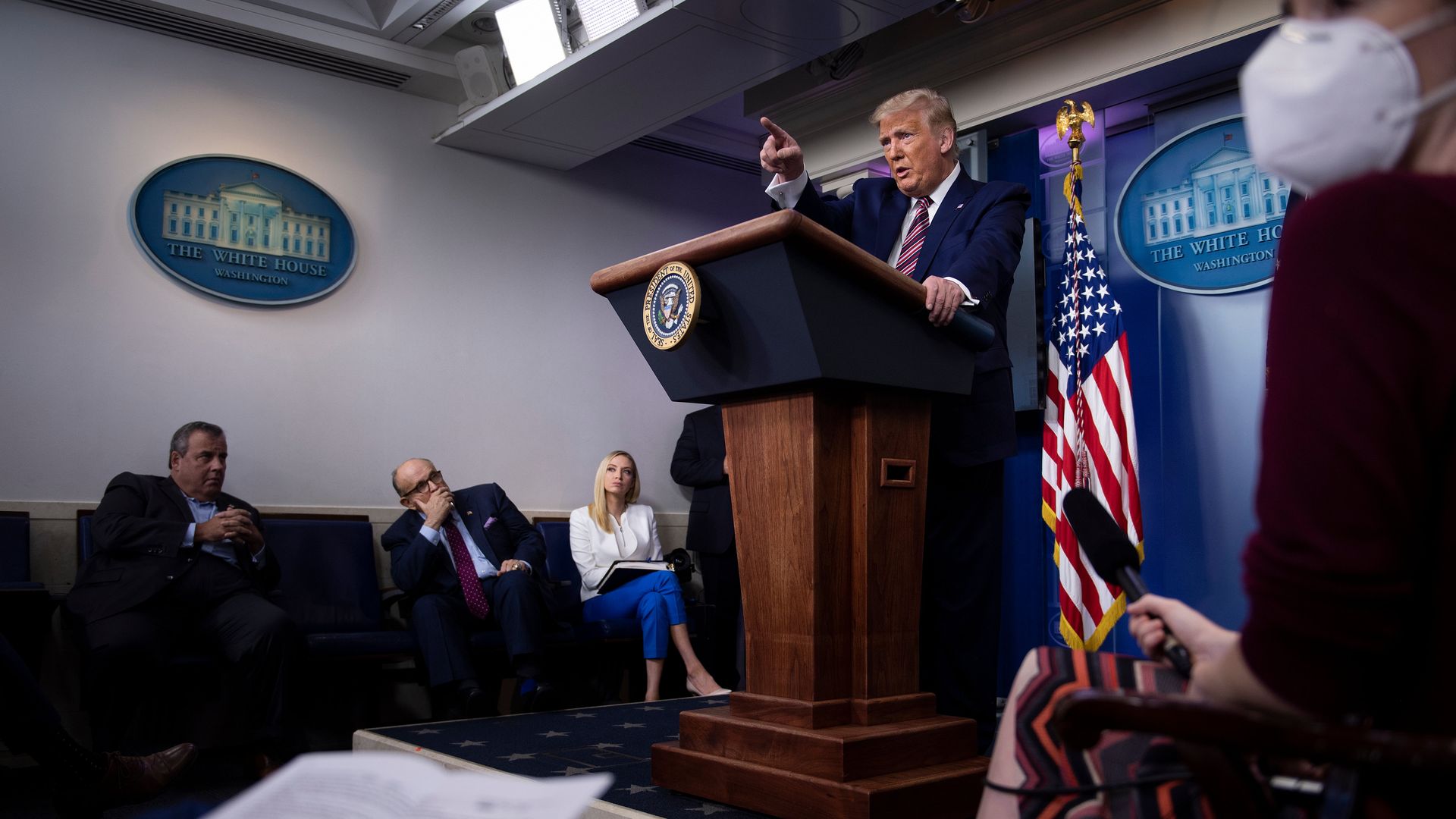 Photo of Donald Trump speaking from behind a podium with others watching on