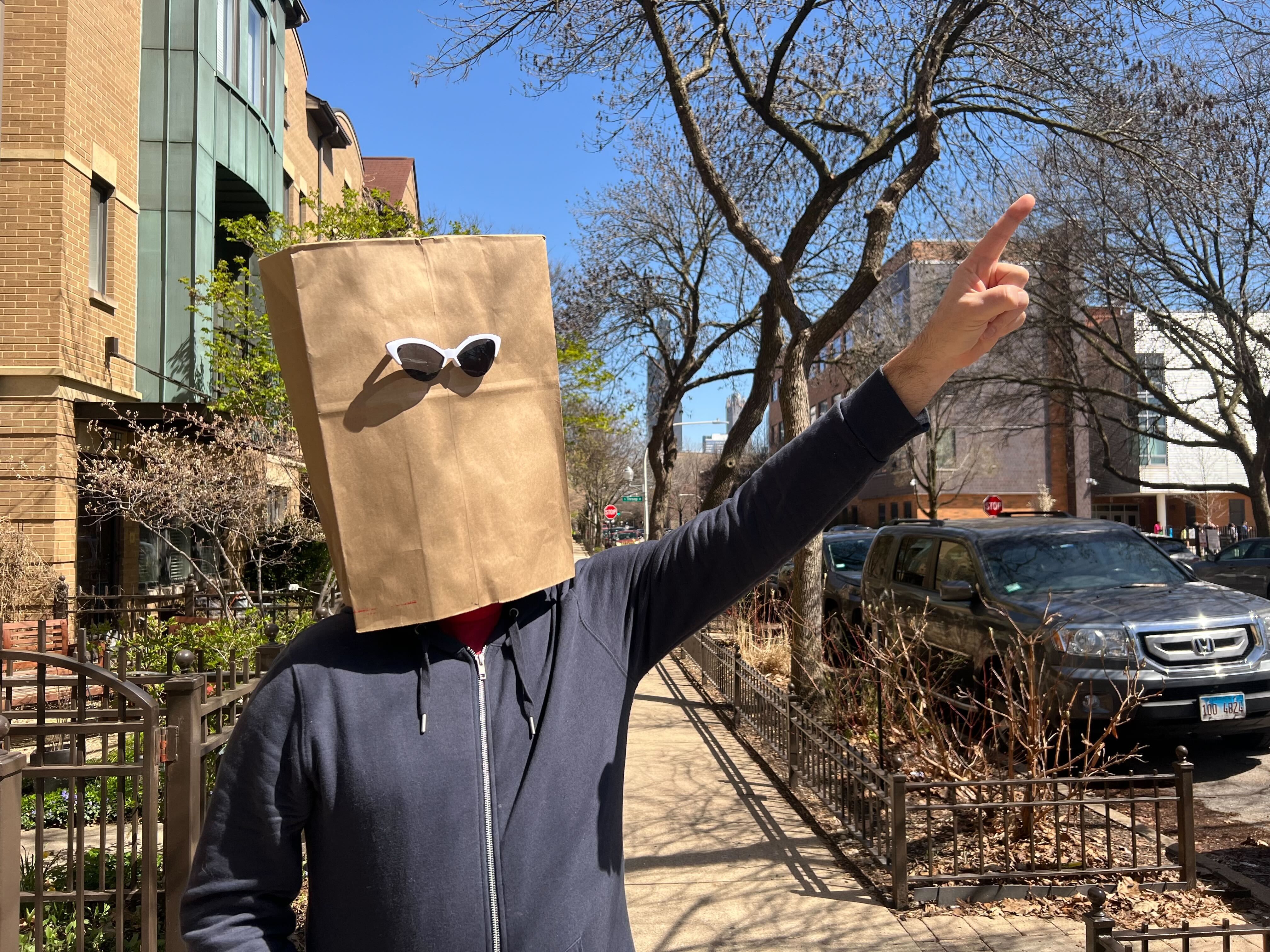 Photo of a man with a bag over his head pointing 