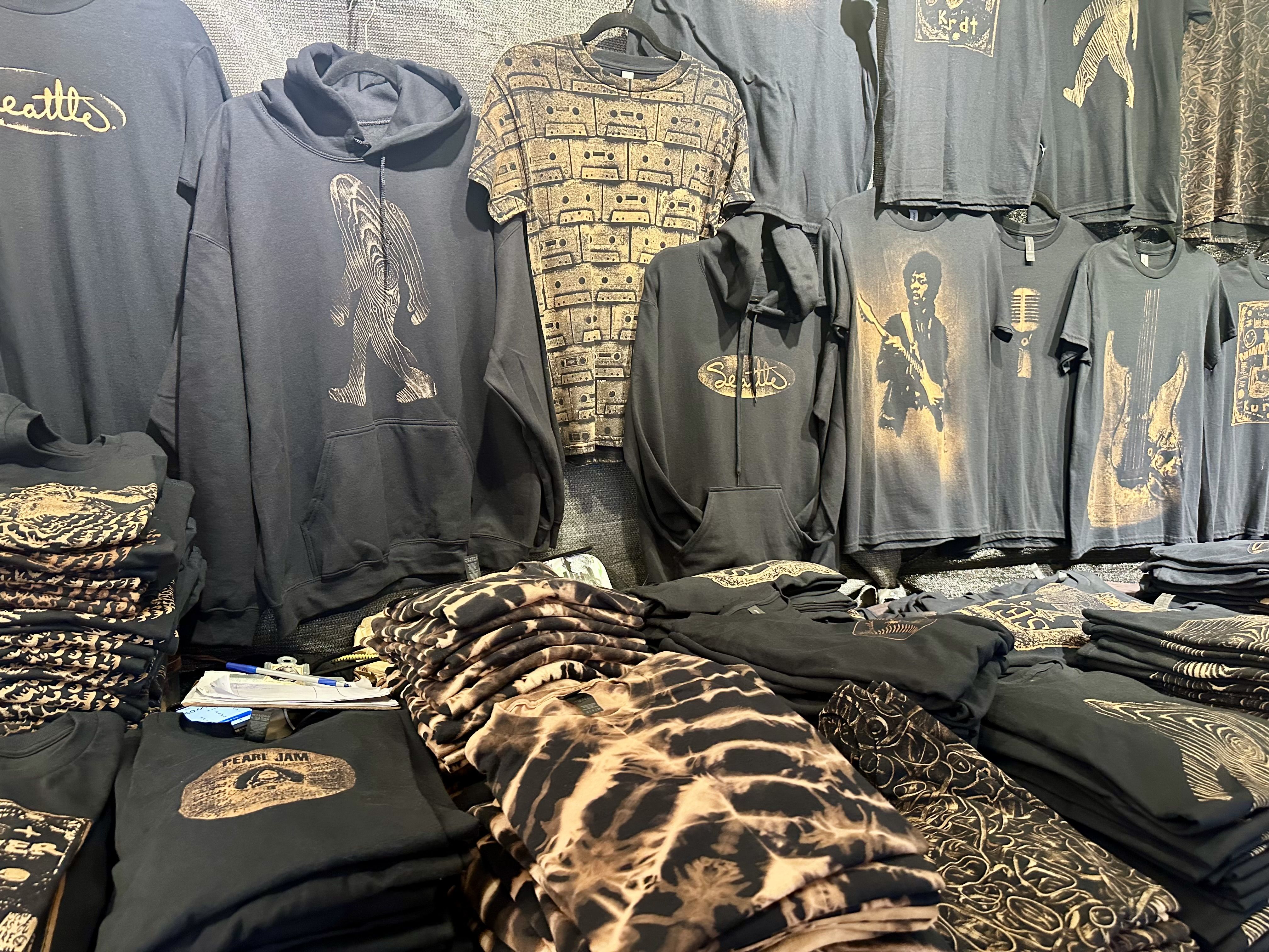 Black tees and hoodies imprinted with brown and white designs made from bleach and coffee, including T-shirts with guitars, Jimi Hendrix and more.