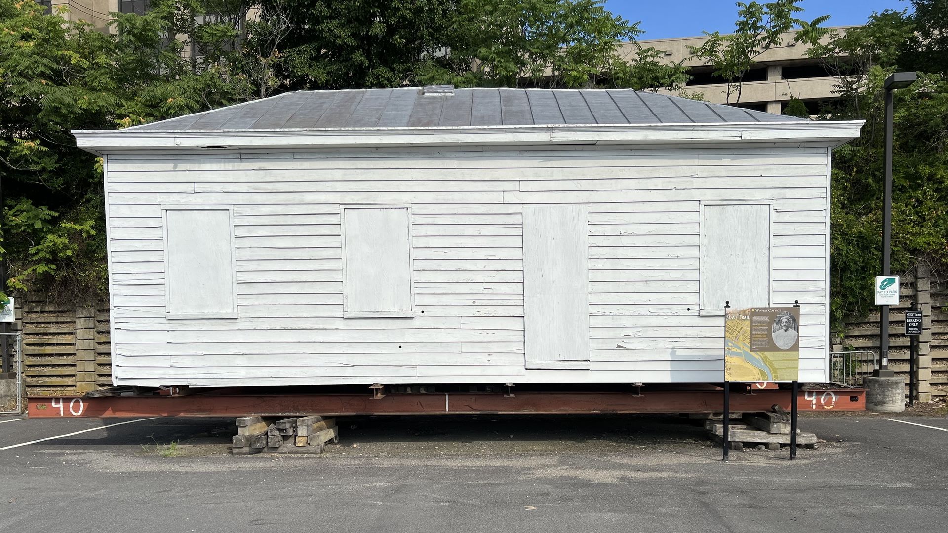 An old, boarded up white building on a trailer.