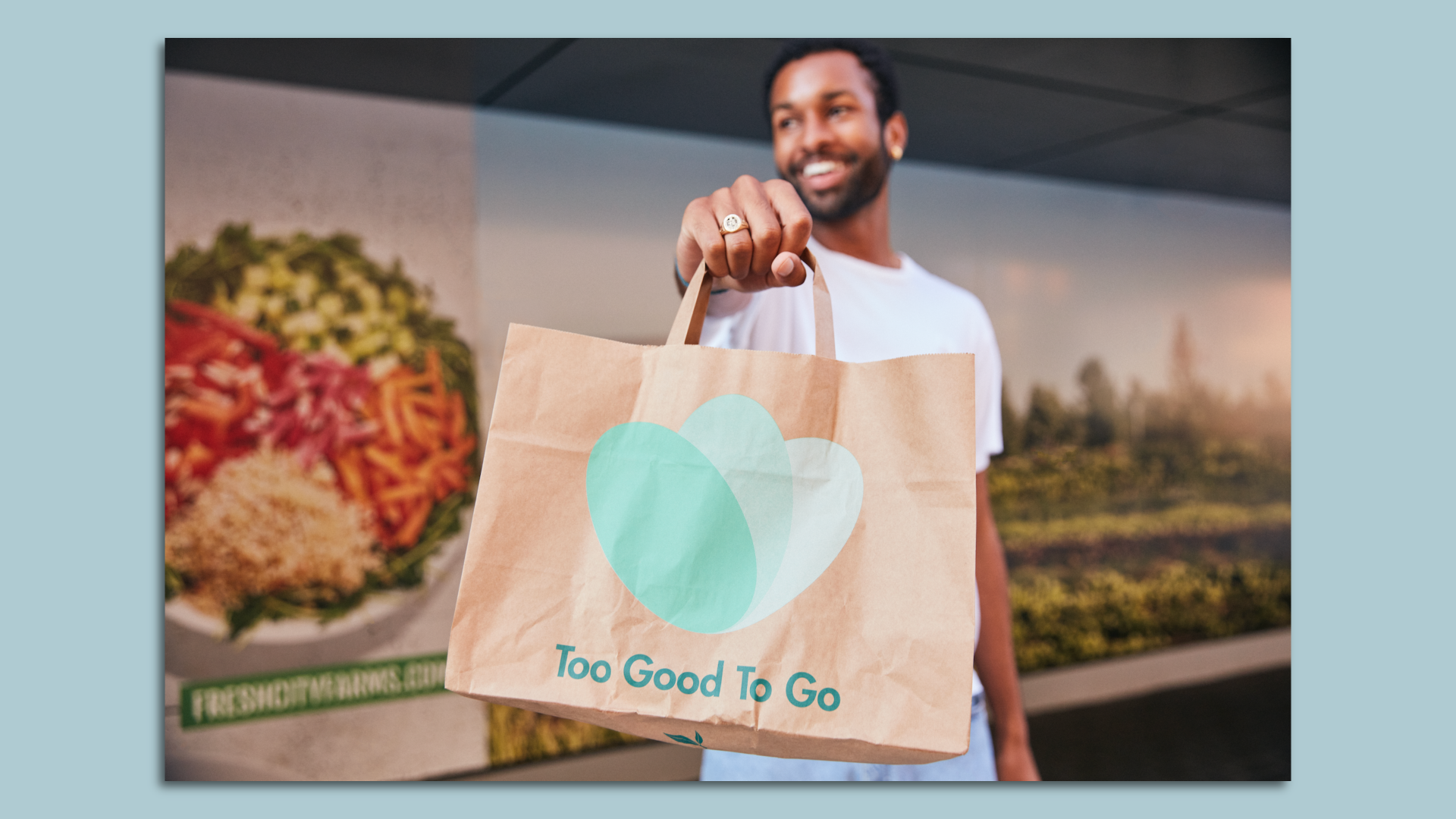 A person is pictured holding a bag of surplus food from the company Too Good To Go.
