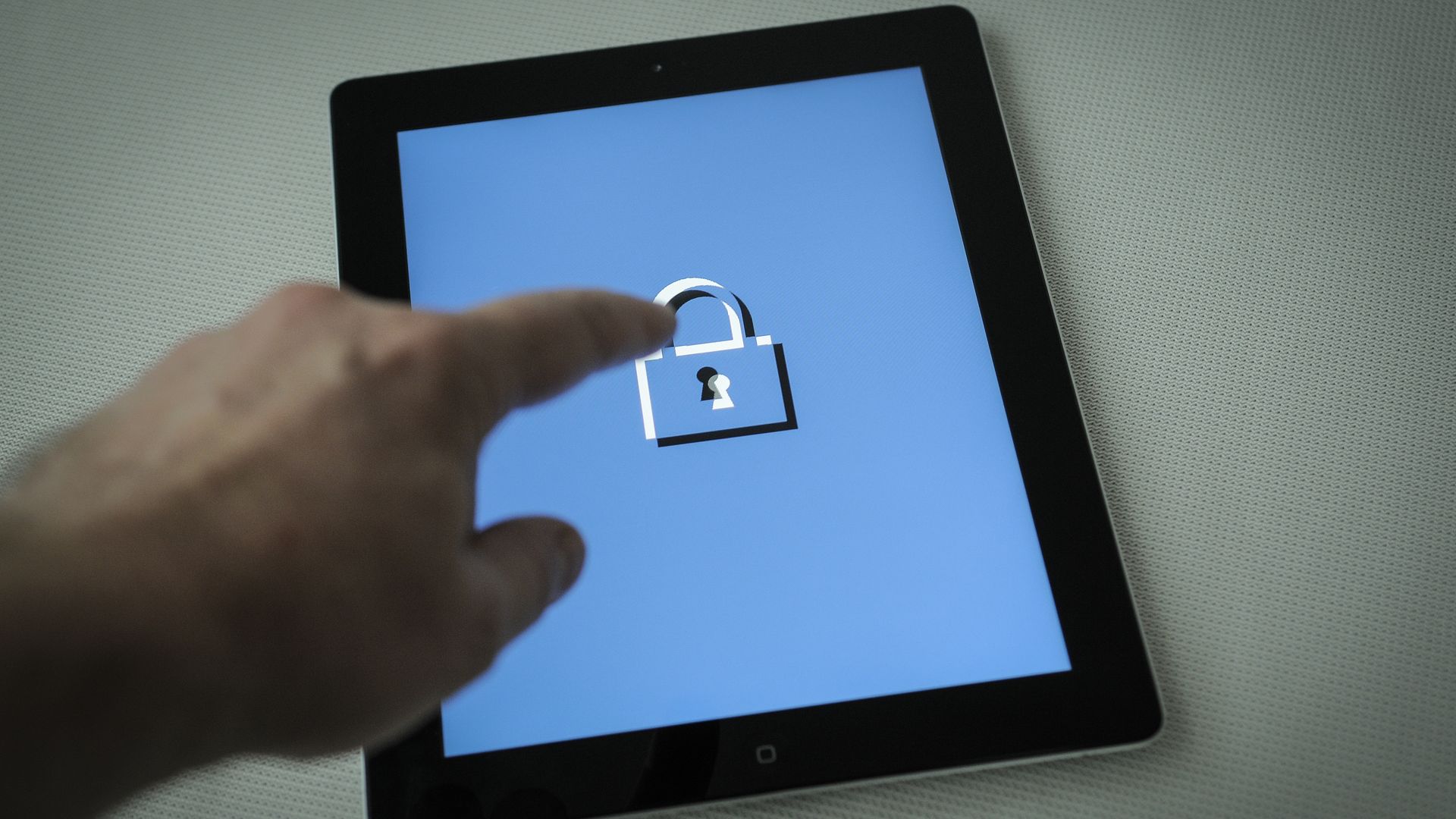 Finger pointing at a lock illustration on a tablet