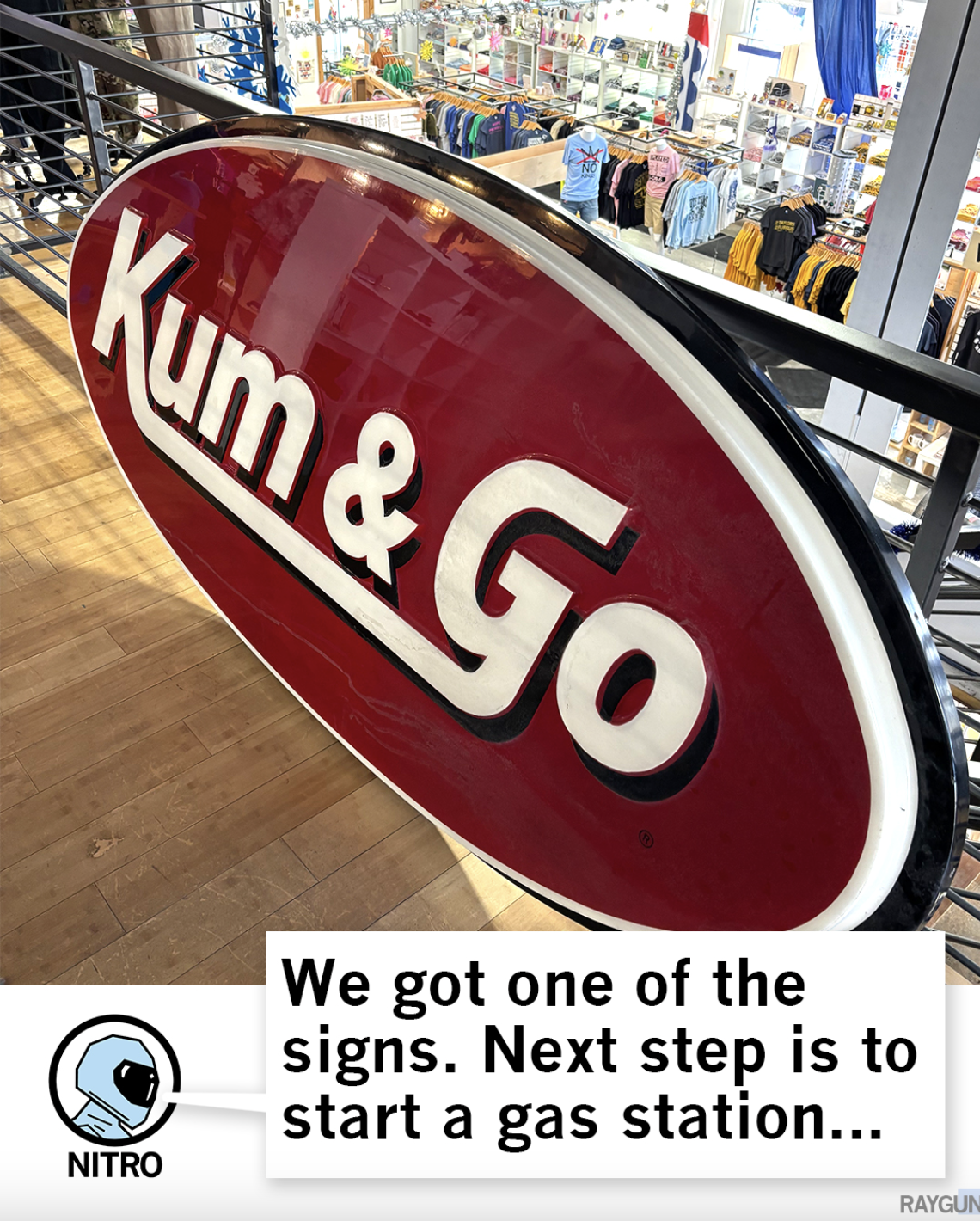 A Kum & Go sign in the Raygun store with an astronaut graphic saying, "We got one of the signs. Next step is to start a gas station...."