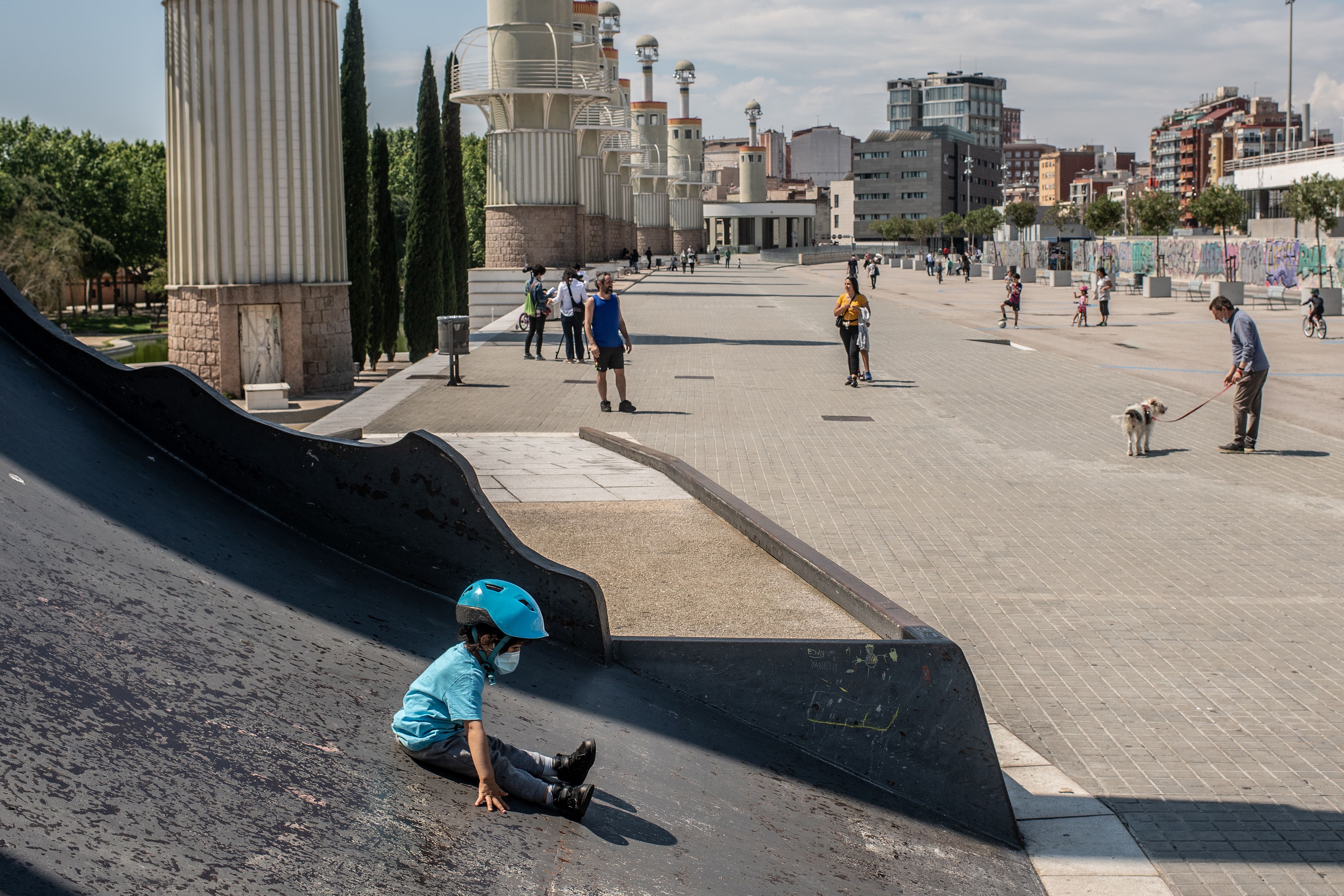 In this image, a boy wearing a helmet and face mask sits in Barcelona Spain