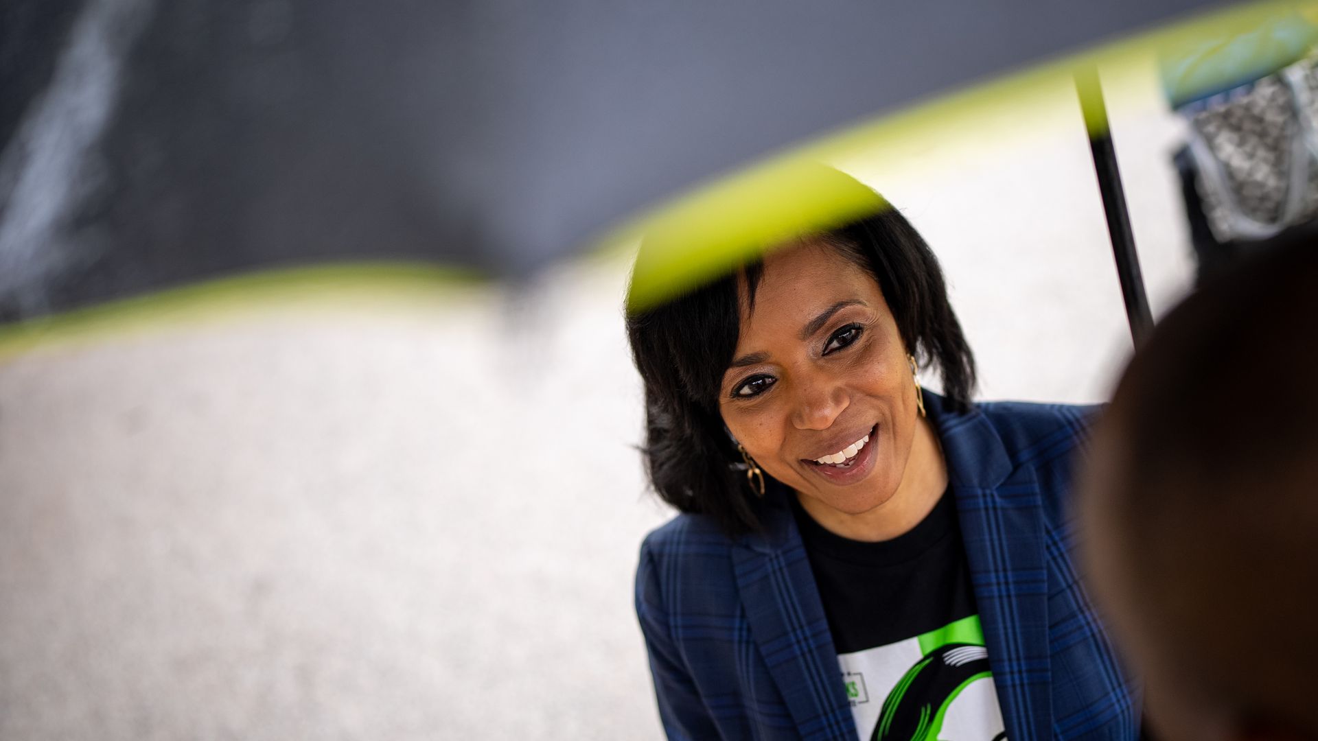 Angela Alsobrooks, carrying an umbrella, smiles at a voter.