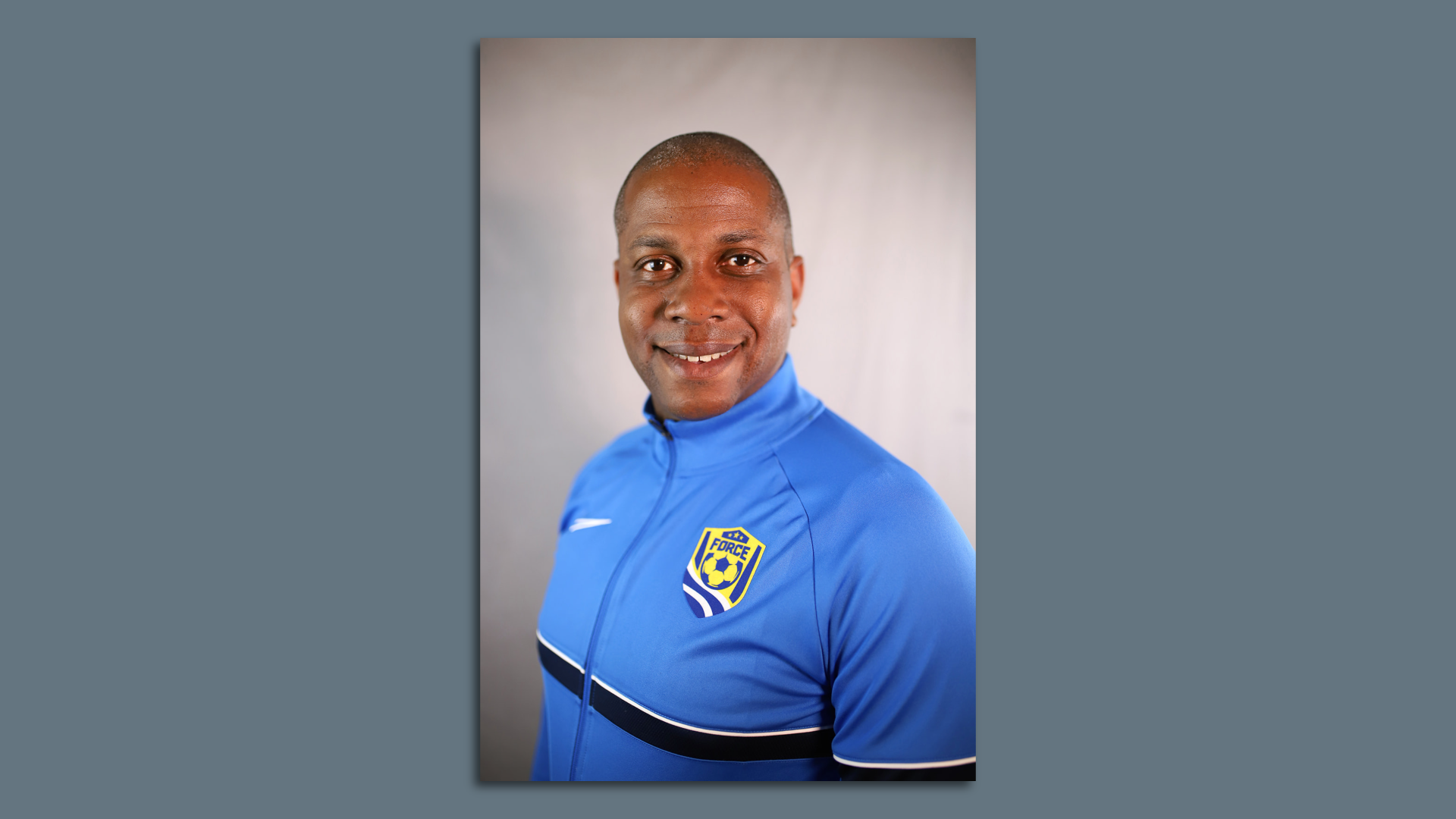 Headshot of an African American soccer coach in blue track jacket
