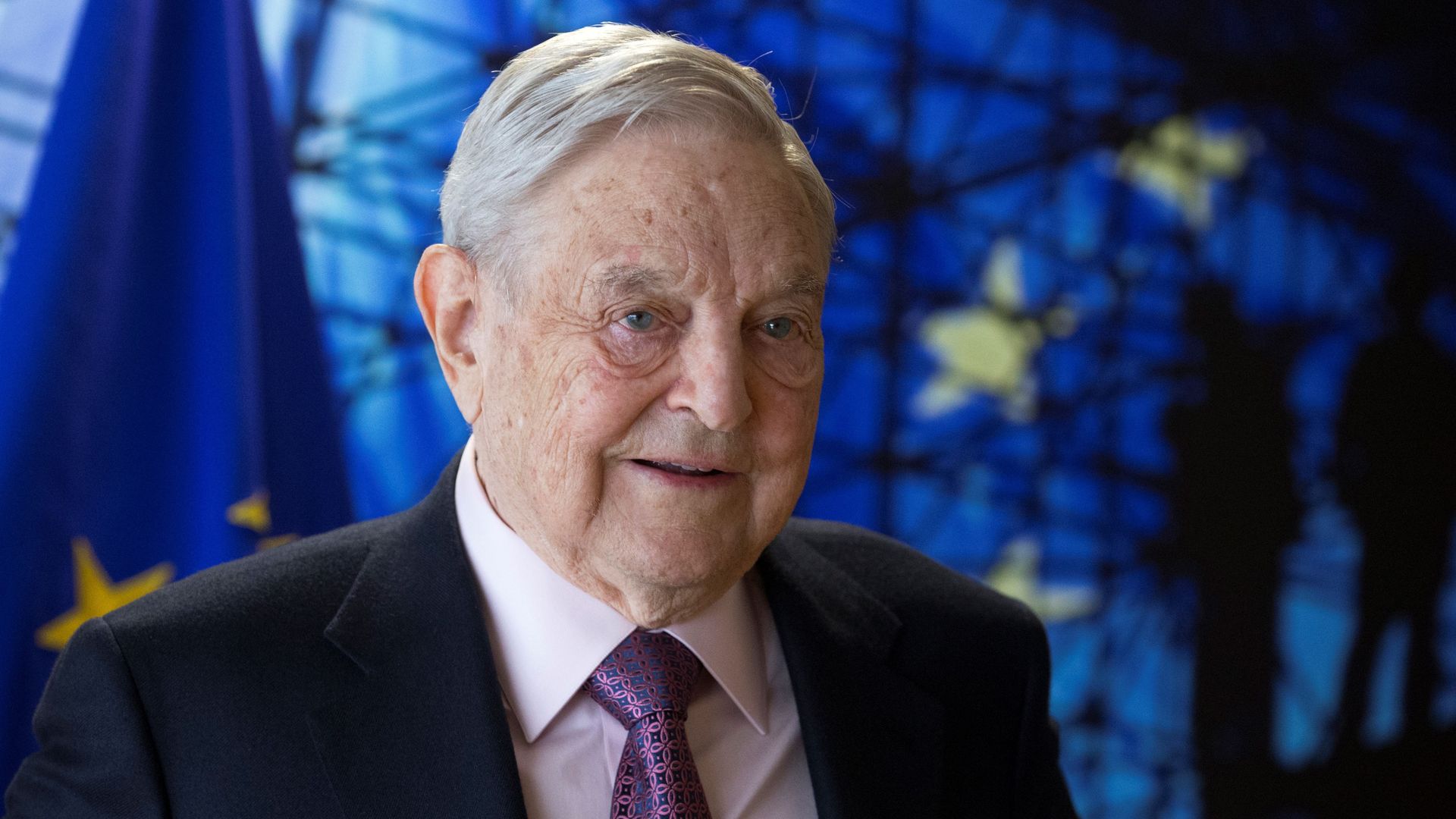 George Soros in front of the flag of the European Union
