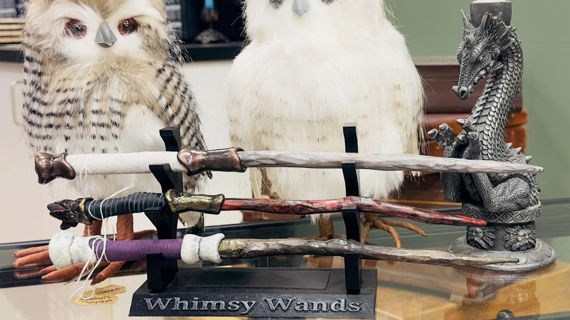 Two stuffed owls with three wands stacked in front of them