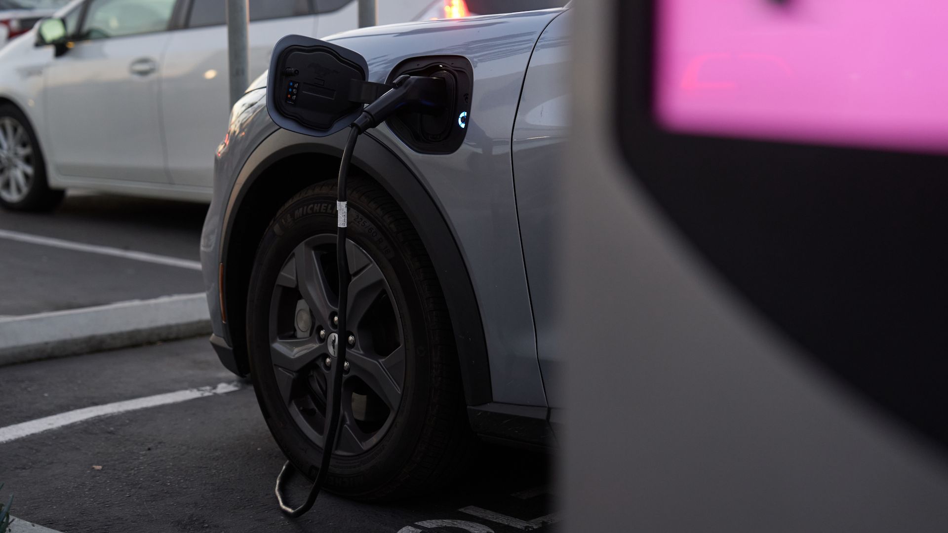 A vehicle is plugged into an EV charger in a parking lot.