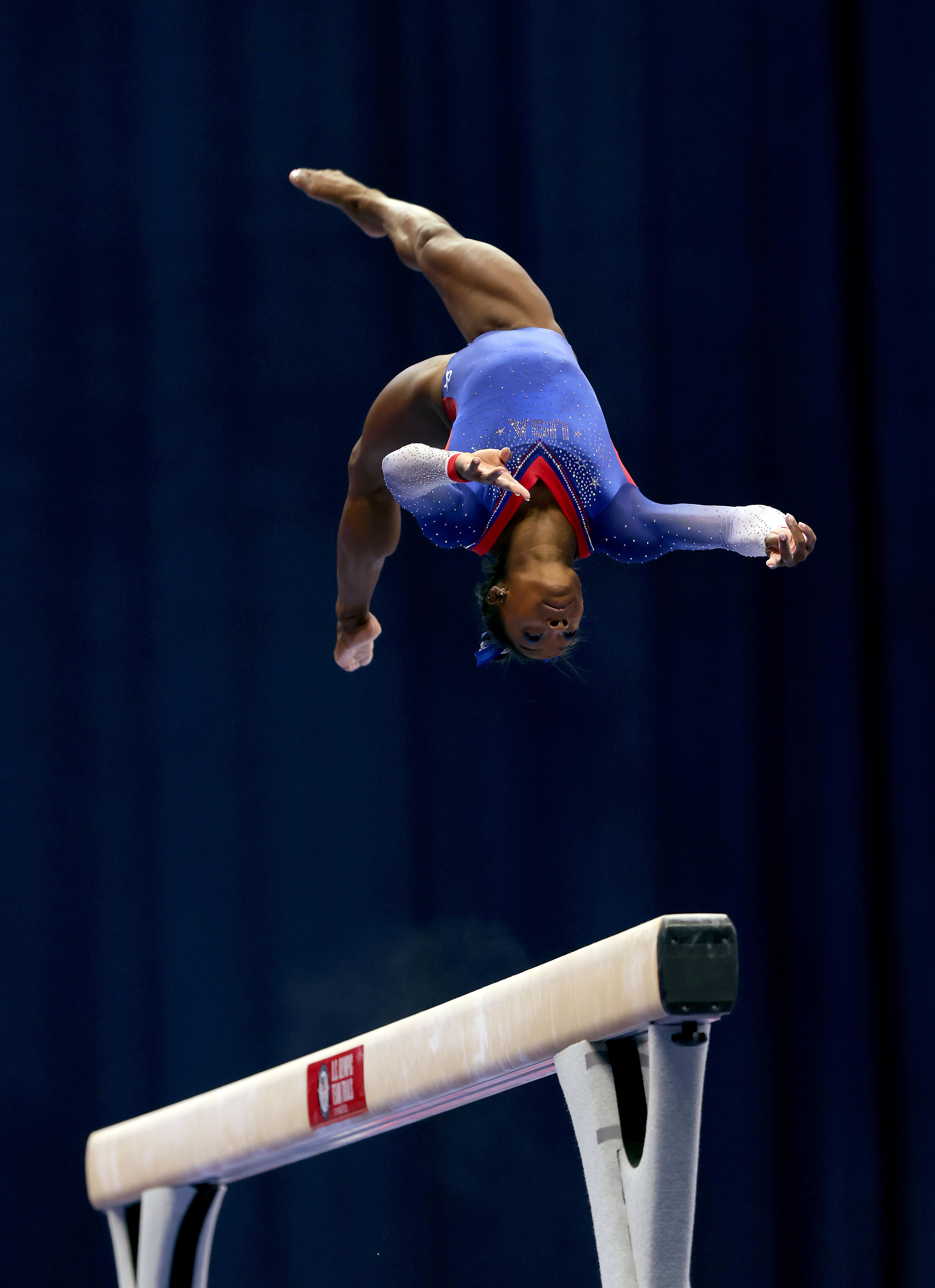 Simone Biles performing a flip above a balance beam