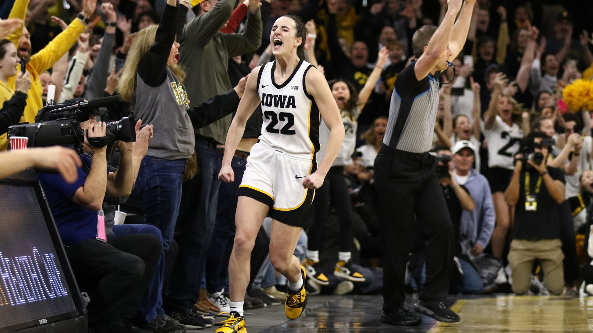 Caitlin Clark celebrates along the sideline with fans cheering 