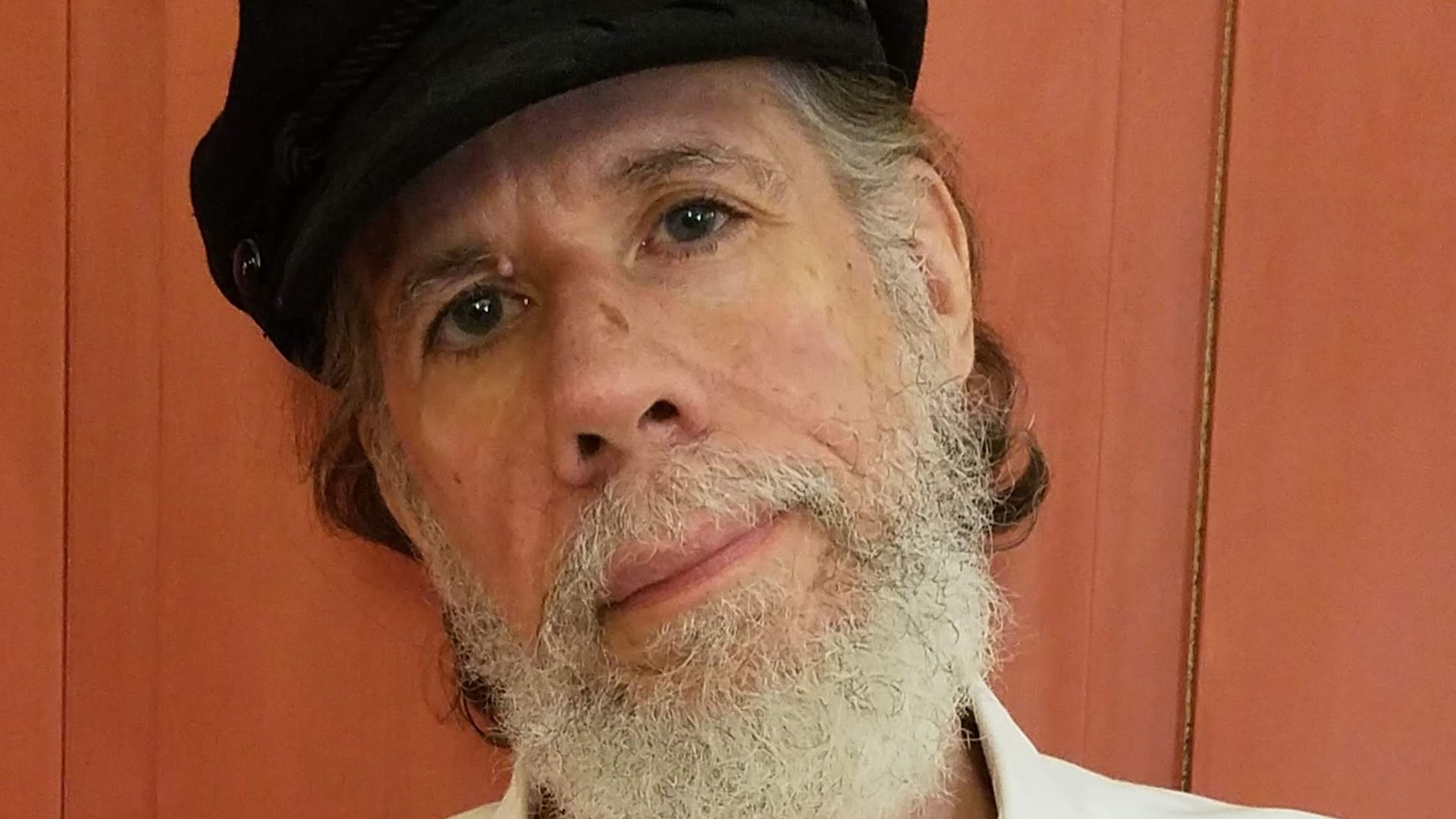 Martín Espada stands for a photo with a black hat.