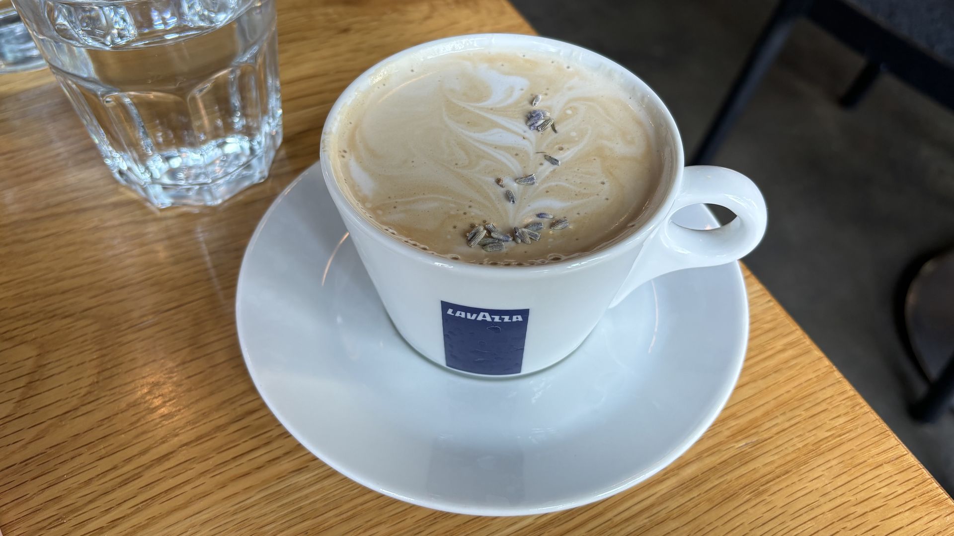 A latte with flower petals on top of it on a table. 