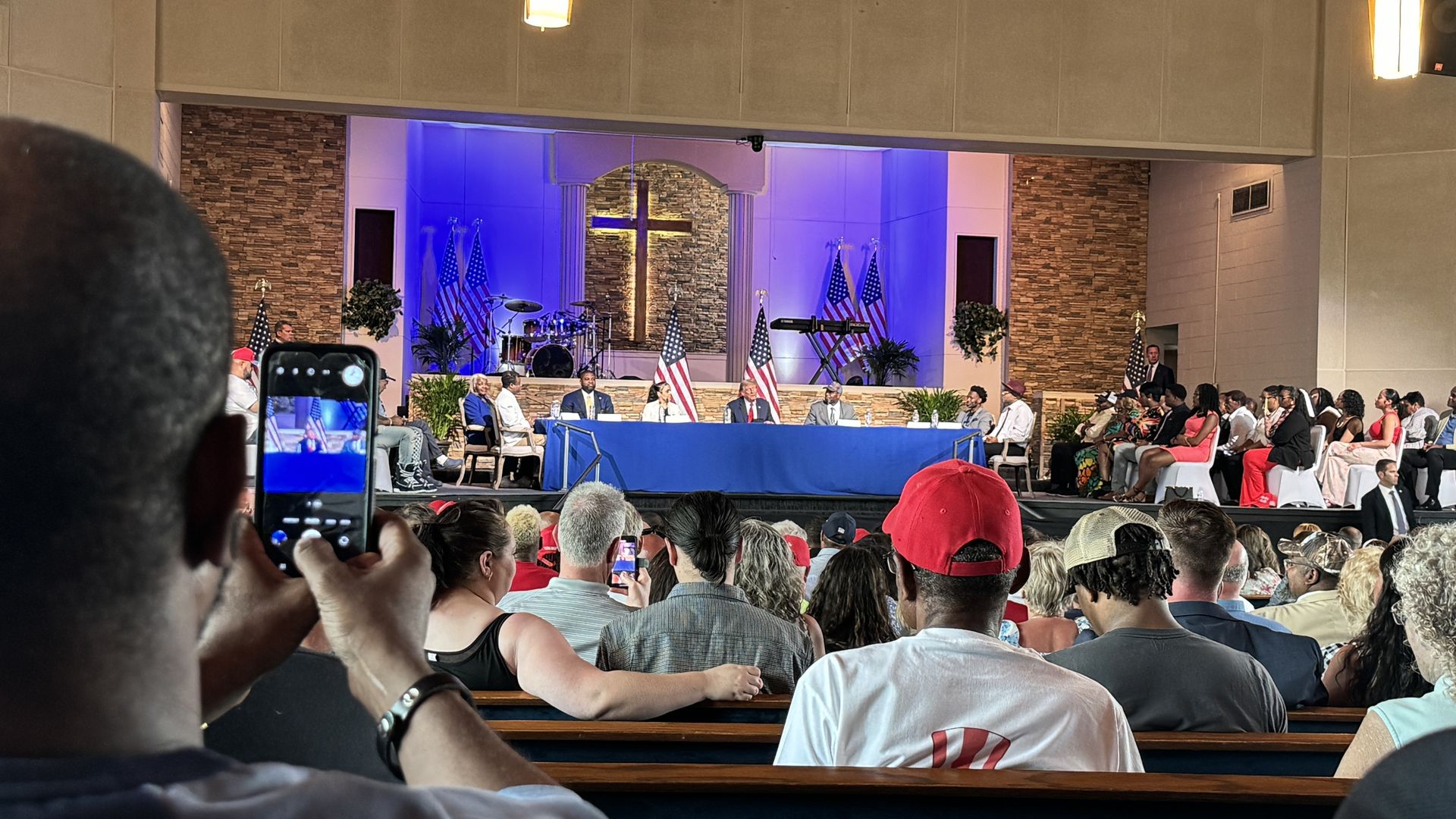 Former president Donald Trump on stage next to U.S. Rep. Byron Donalds (R-Fl), convenience store owner Itasha Dotson, boxing coach Carlos Chambers,180 Church pastor Lorenzo Sewell 