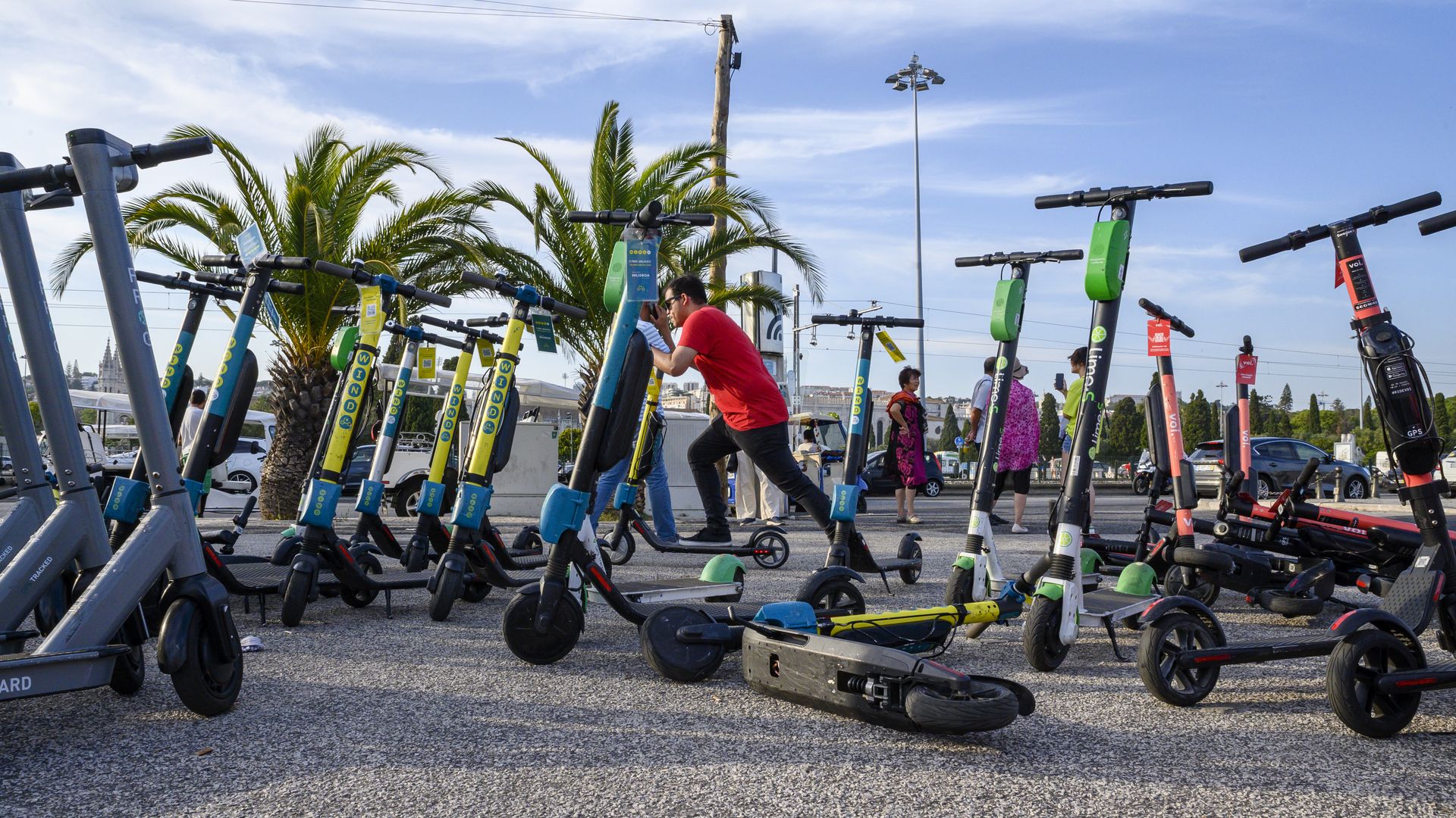 A man starts an e-scooter by a group of others left on an esplanade in Lisbon, Portugal