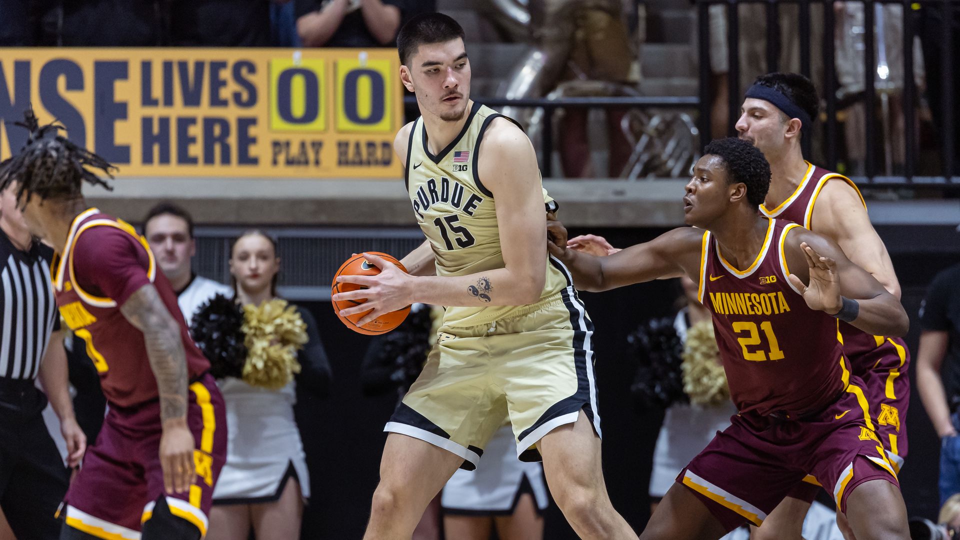 Zach Edey, with a basketball, backs down a Gophers player