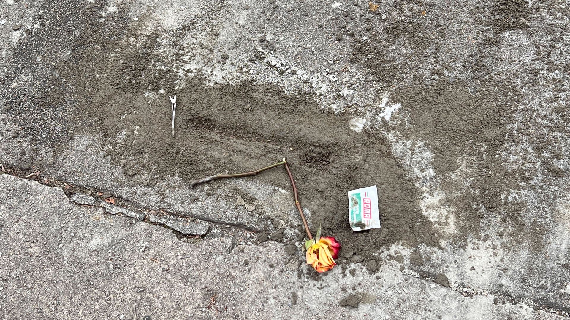 a partial full concrete sidewalk hole where the faint outline of a gun can be seen. 