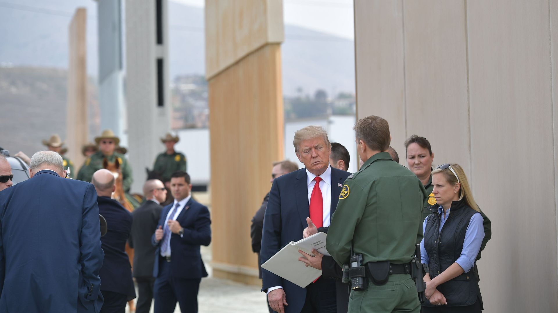 Donald Trump looking at something next to border wall stuff