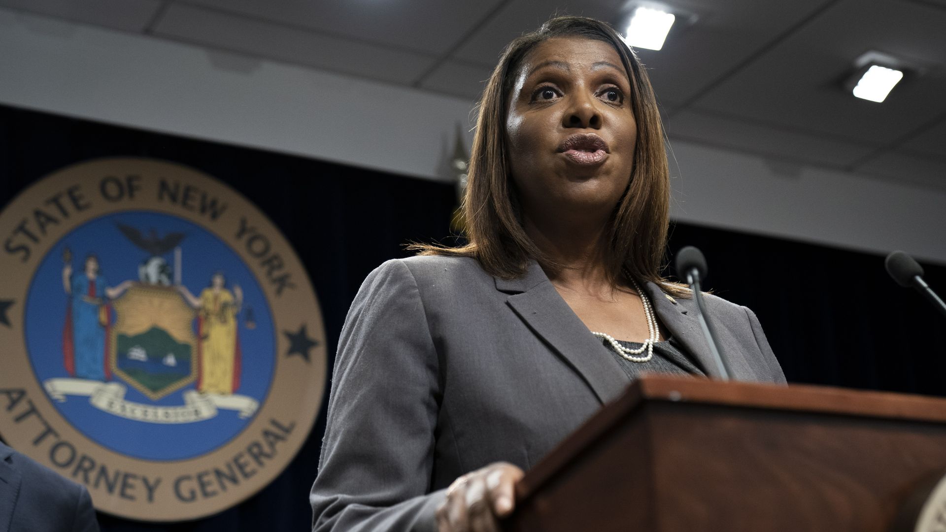 Photo of NY State Attorney General Letitia James at a lectern with official seal behind her