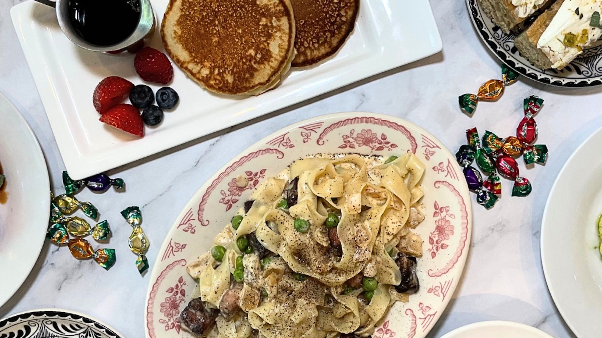 A table with brunch plates like pancakes and pasta carbonara