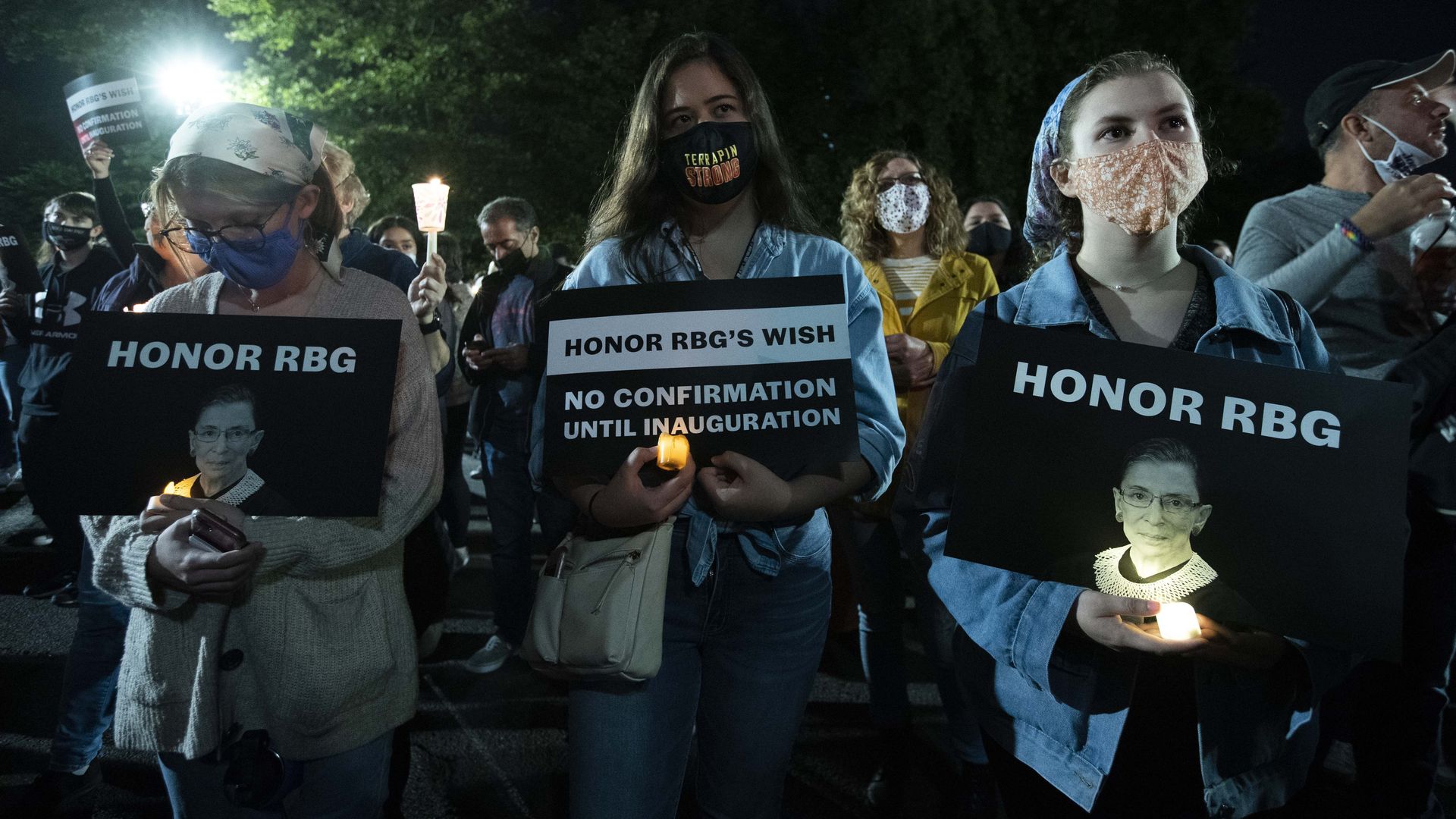 People holds signs and candles as they pay their respects to Ruth Bader Ginsburg near the US Supreme Court