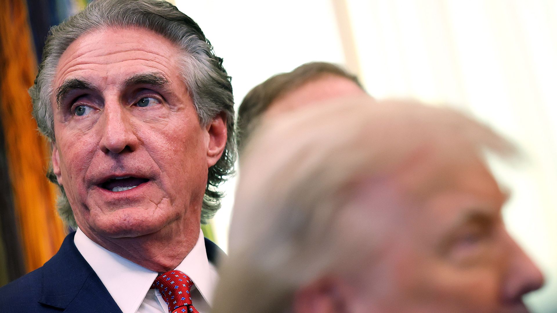Doug Burgum is photographed with an out-of-focus Donald Trump in the foreground