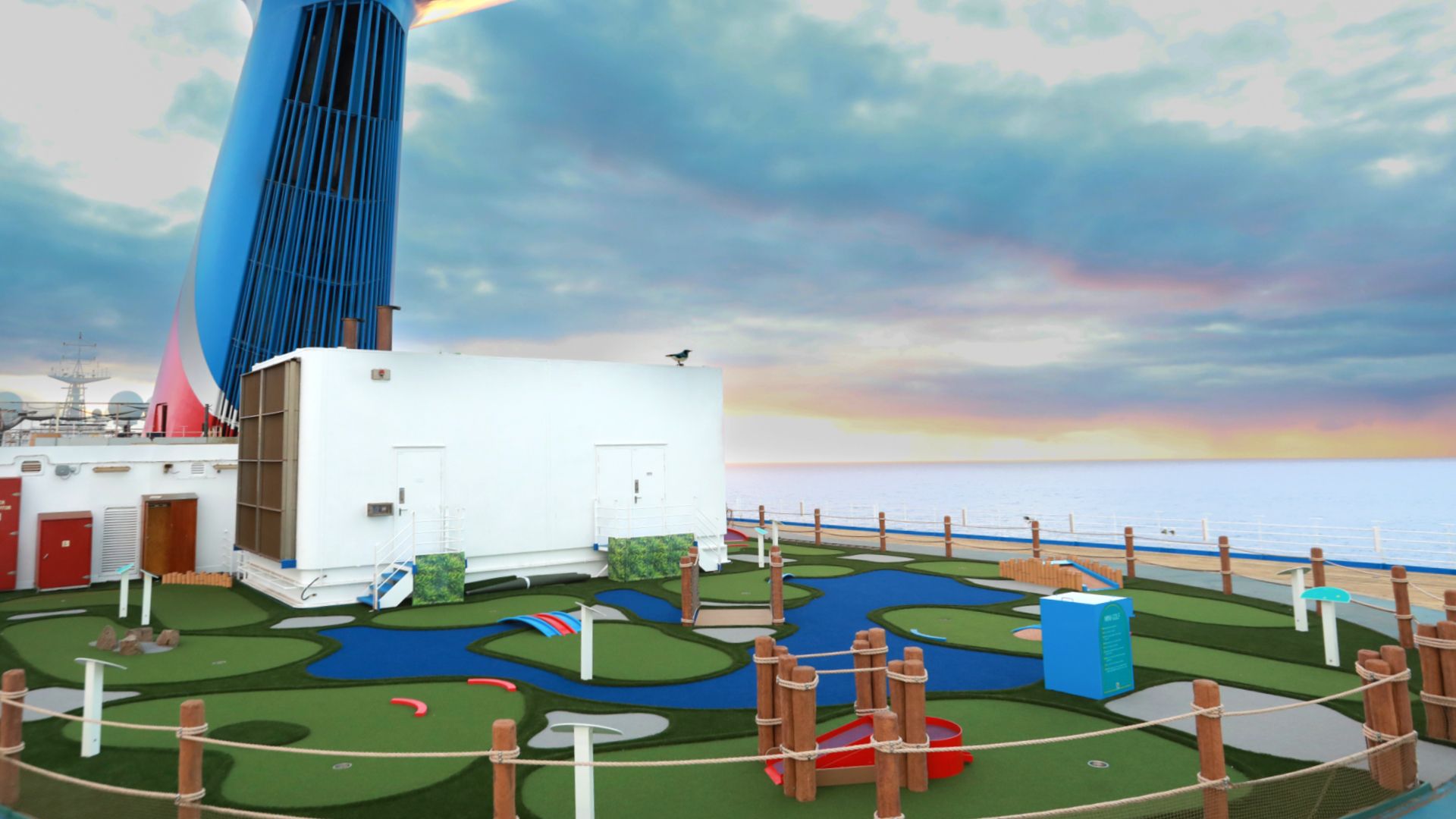 A mini-golf course is seen atop a cruise ship, with open water in the distance.