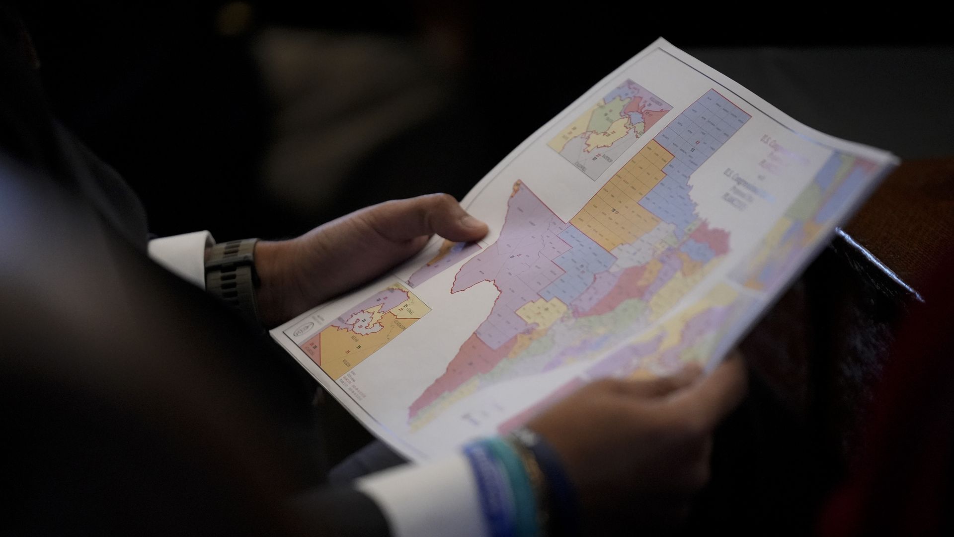 A Texas representative holds at a congressional map of Texas in his hands.