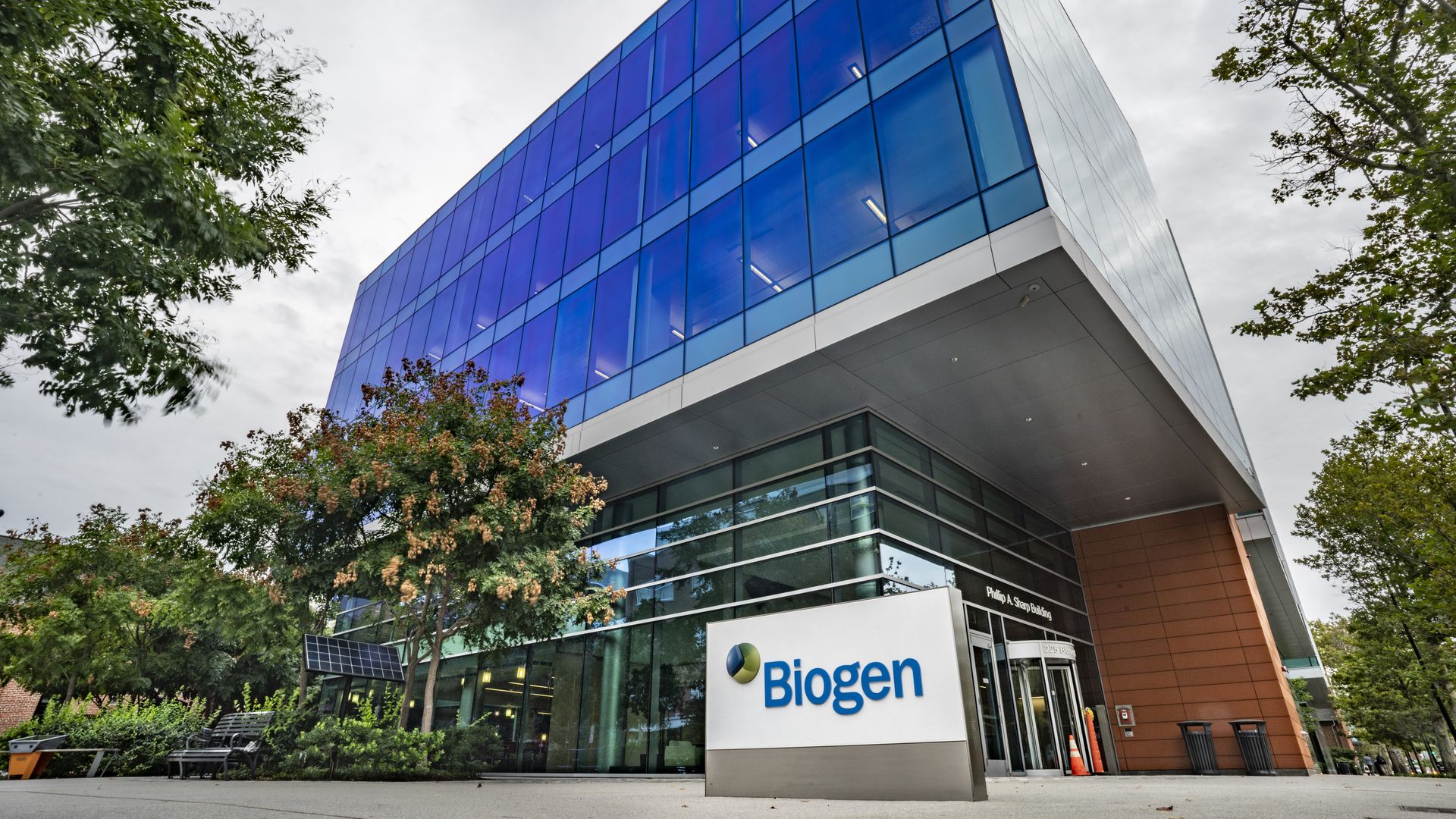 A building with blue windows and a white sign with Biogen in a blue font.
