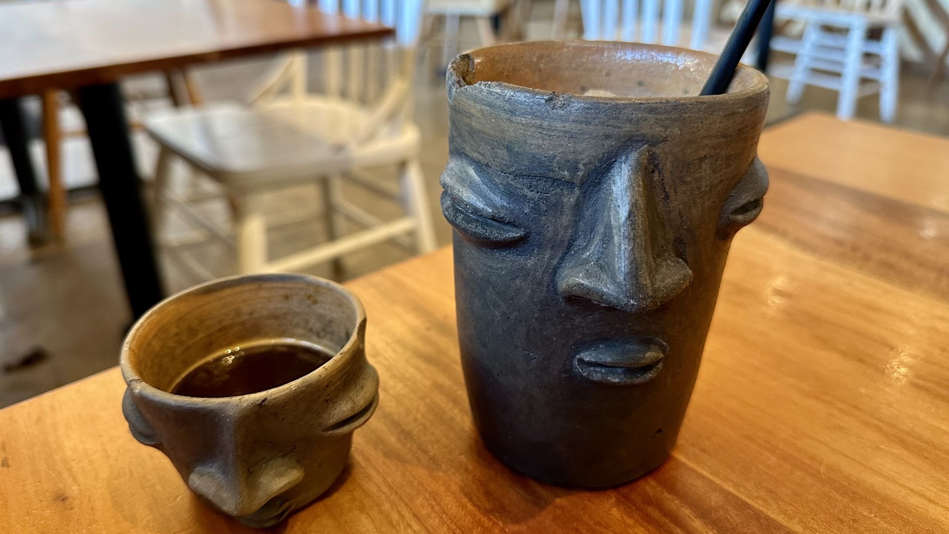 Two clay cups on a table holding espresso and horchata