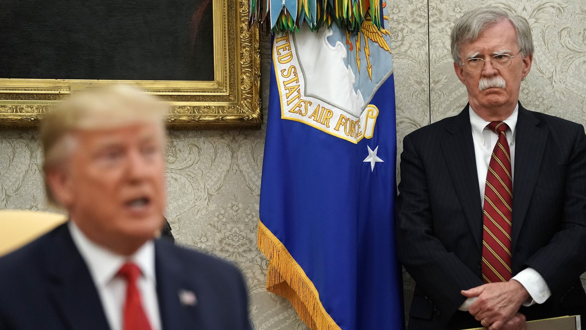 White House National Security Advisor John Bolton (R) listens to U.S. President Donald Trump in the Oval Office at the White House July 18