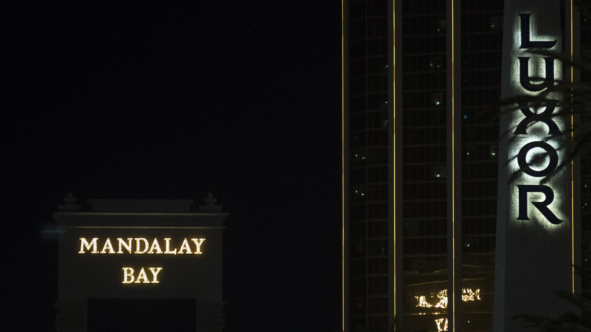 Mandalay Bay logo lit up in yellow with black background in nighttime.