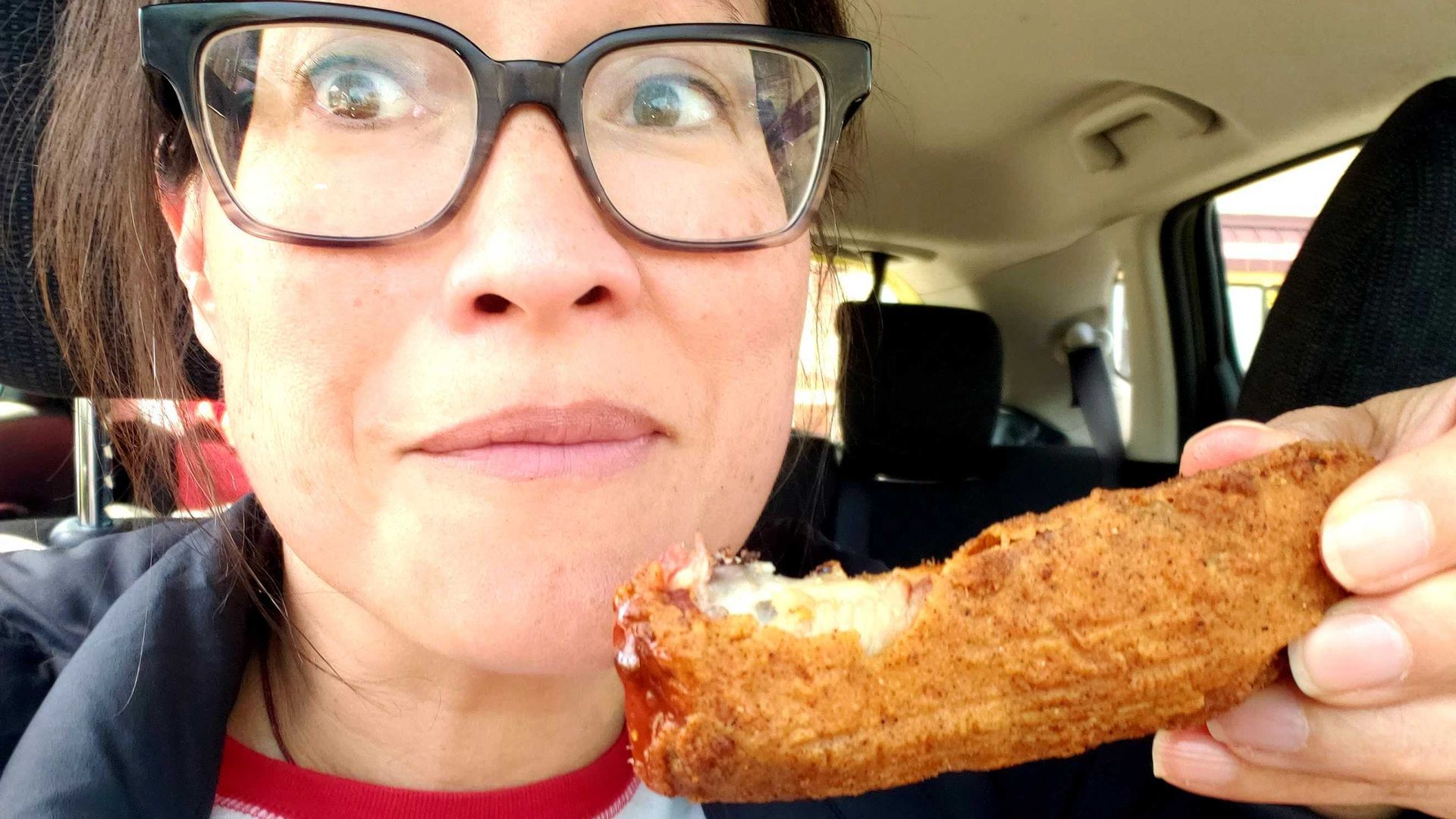 Photo of a woman eating a deep fried rib. 