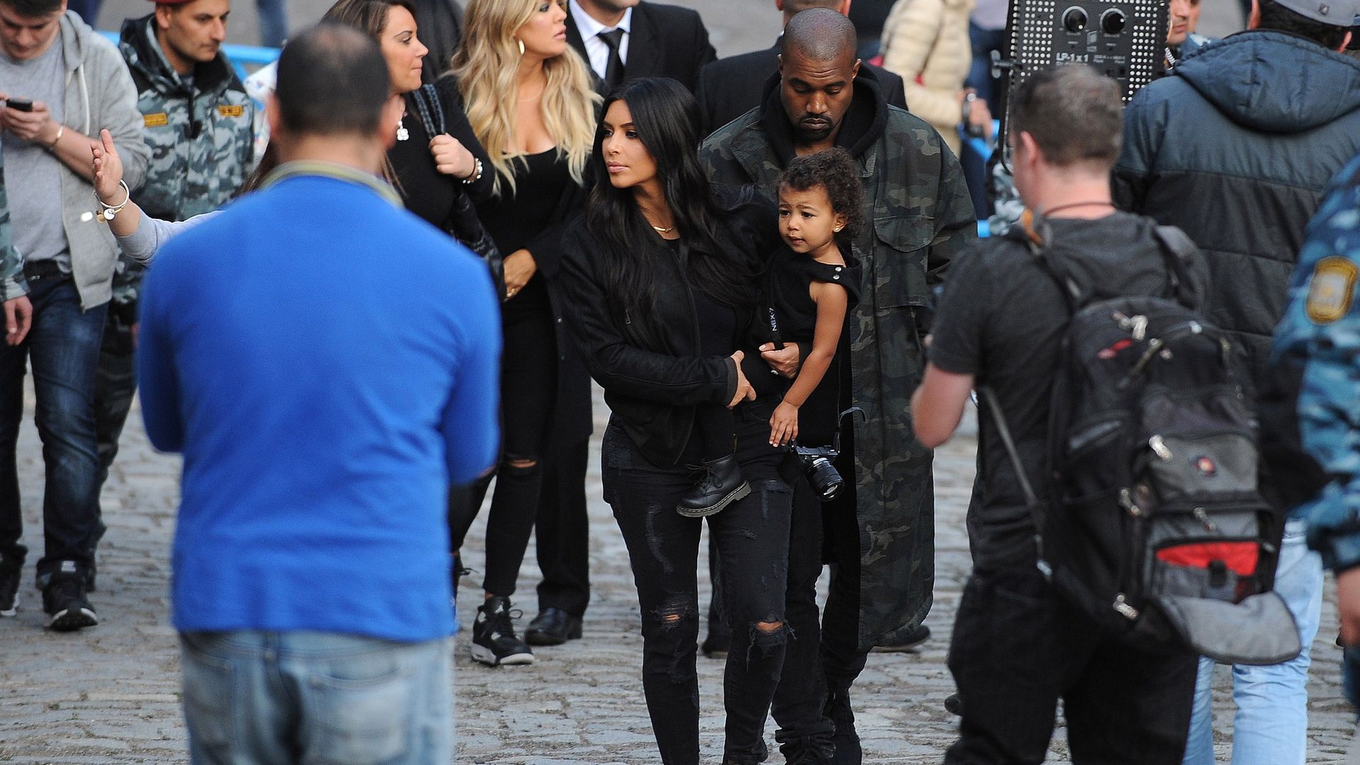 Kim Kardashian carrying her child with Kanye West behind her