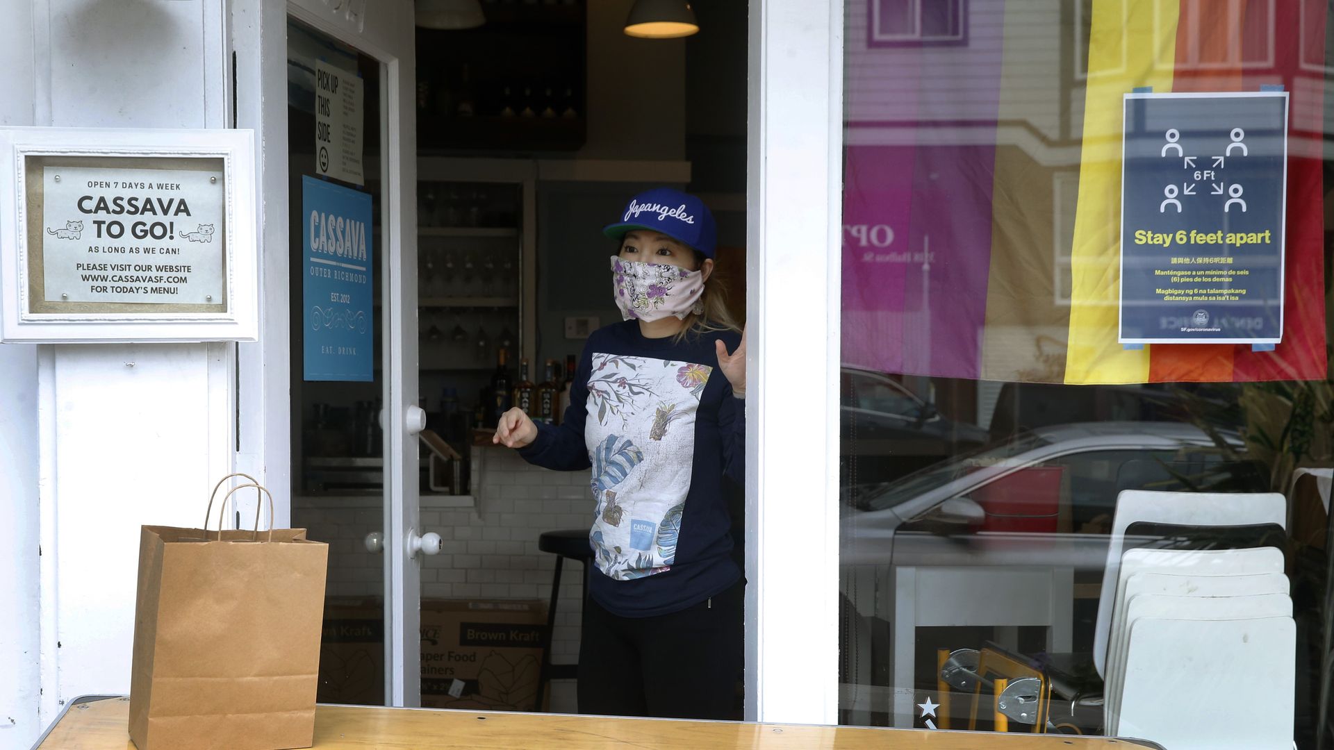 Cassava restaurant co-owner Yuka Ioroi speaks with a customer after bringing a take-out order to the door in San Francisco, Calif