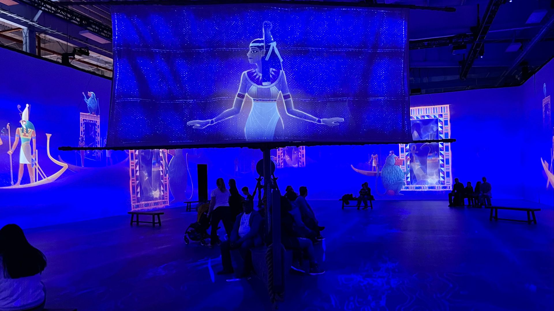 A roomful of visitors surrounded by projected images at the immersive King Tut exhibition.