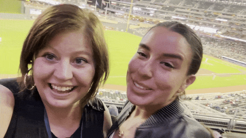 karri and sabrina dancing in front of a baseball diamond 