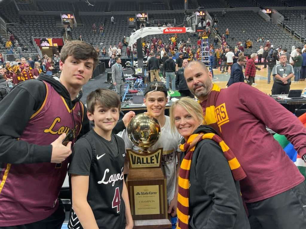 A family poses with a basketball playing son carrying a Missouri Valley conference championship trophy.