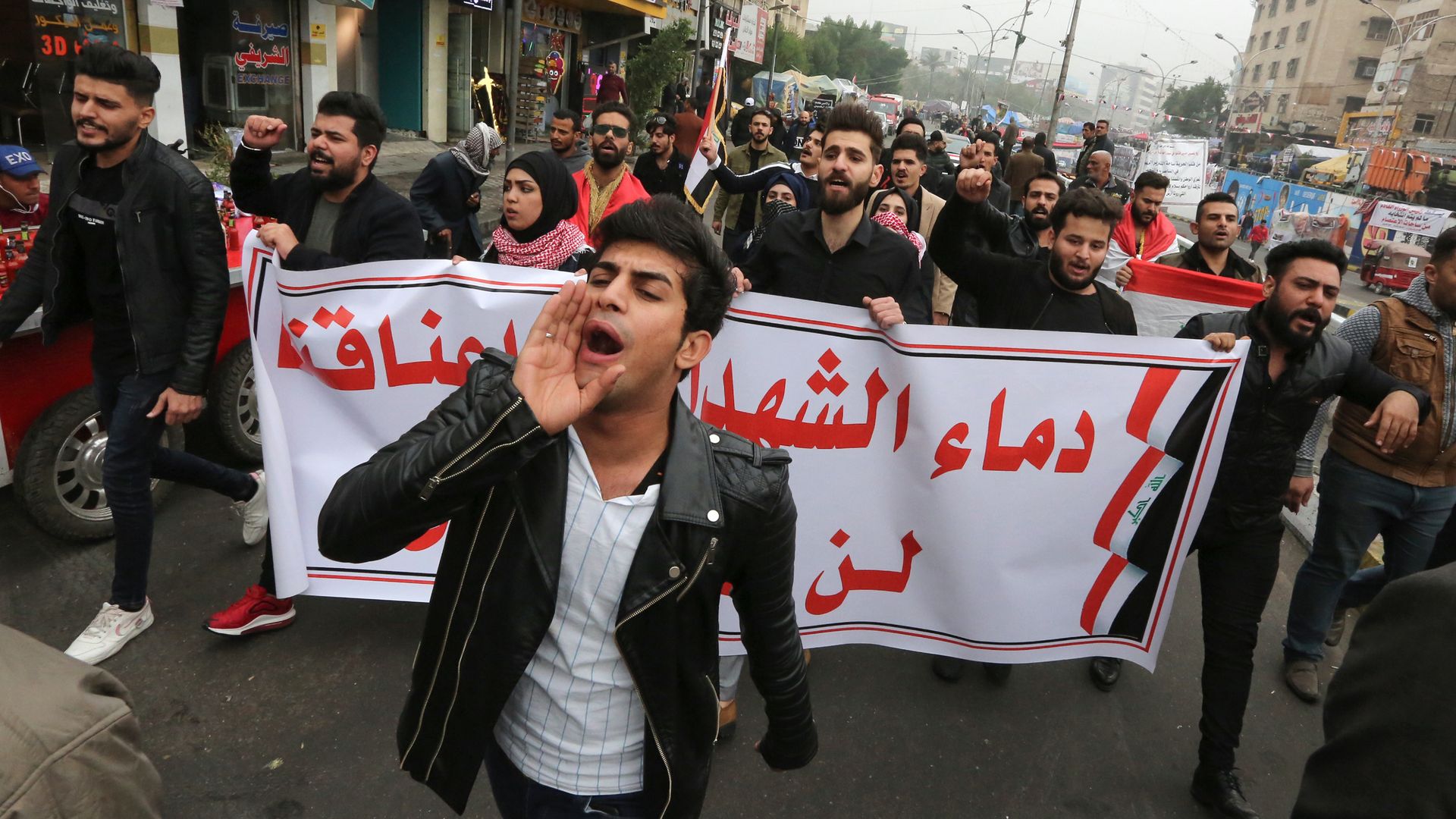 Iraqi protesters carry a banner which reads "The blood of martyrs is entrusted to us, it will not be in vain" during a march in Tahrir Square