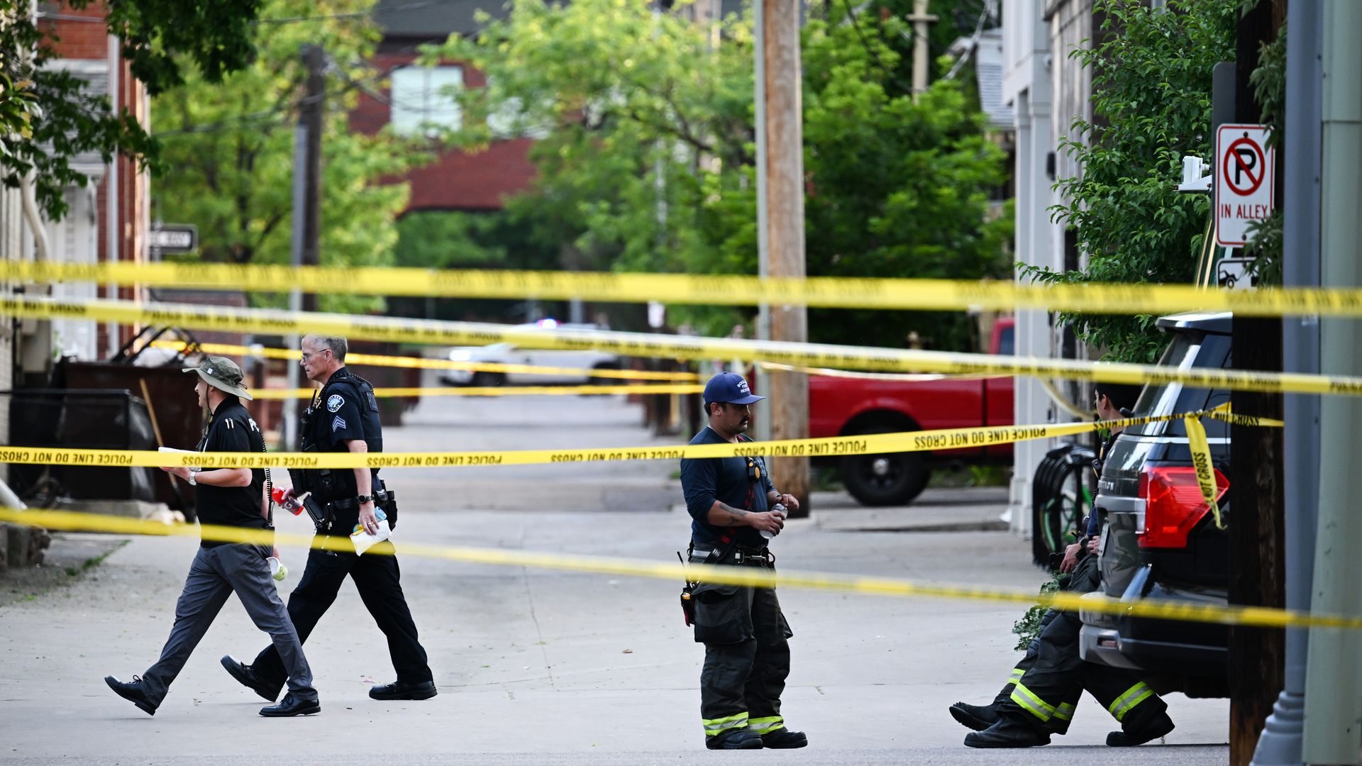 Police and firefighters walk behind police tape in an alley off of Pearl Street.
