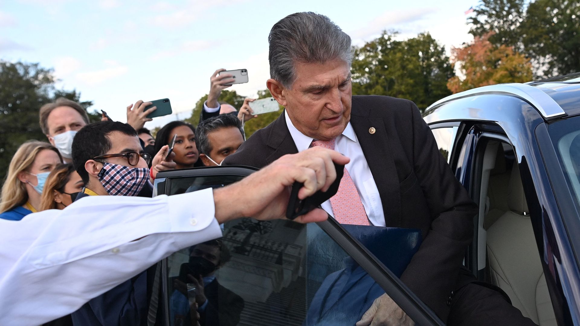 Reporters are seen surrounding Sen. Joe Manchin as he enters a car on Thursday.