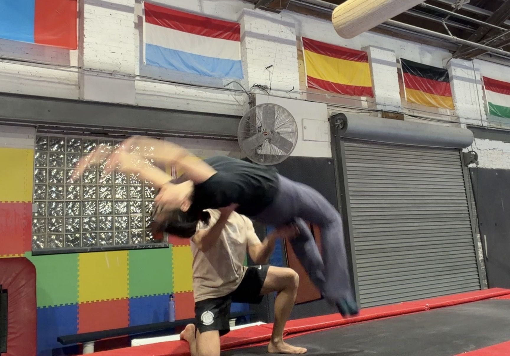 Woman jumping backwards with a spot in gymnastics class. 