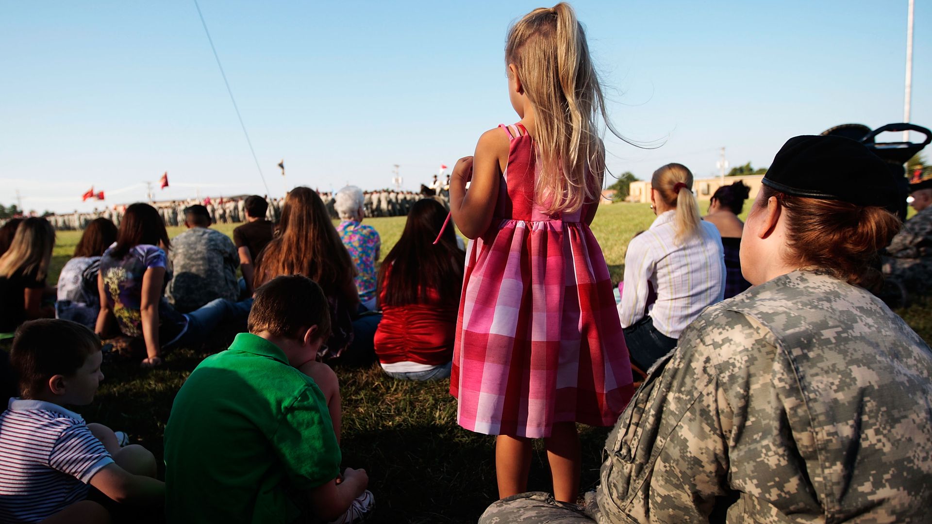A little girl stands and watches a deployment ceremony. 