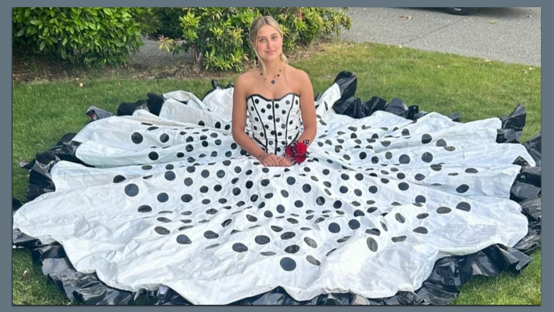 An oversized black-and-white polka dot prom dress made from duct tape spreads in a giant circle around creator Calina Morgan as she sits on a lawn.